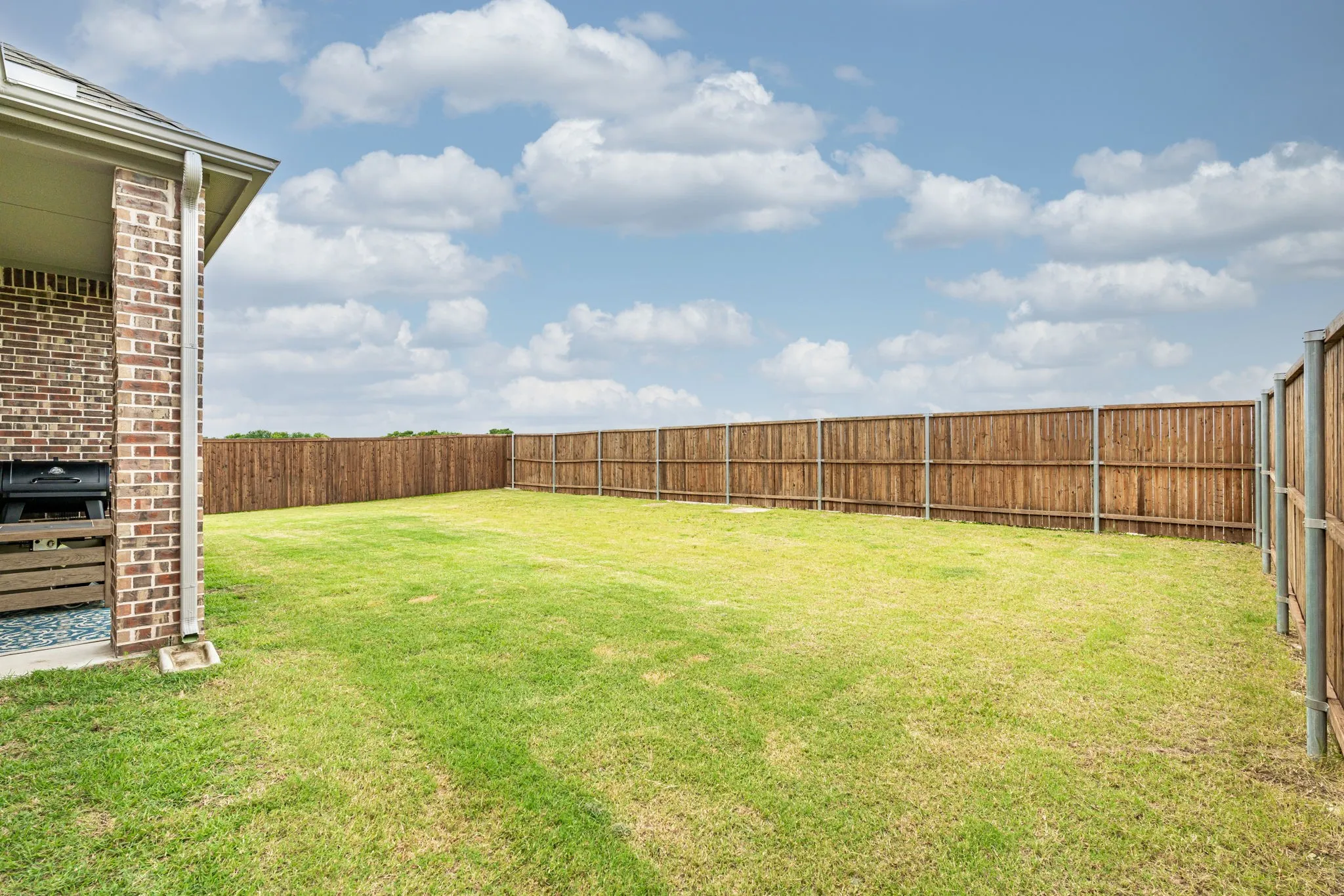 Expansive green lawn with a full privacy fence