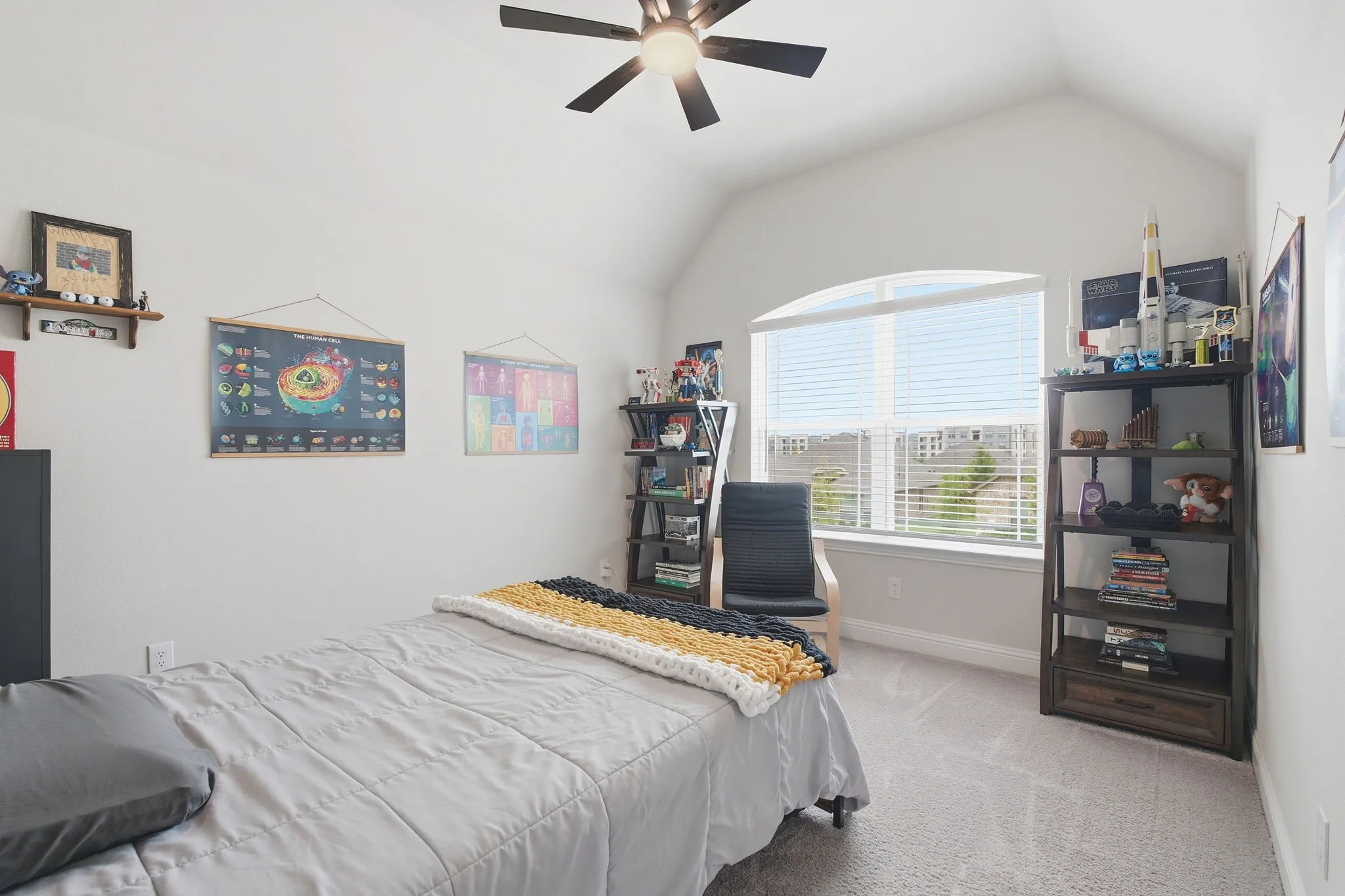 Vaulted ceiling bedroom featuring a large arched window with horizontal blinds, overhead ceiling fan, and carpet flooring