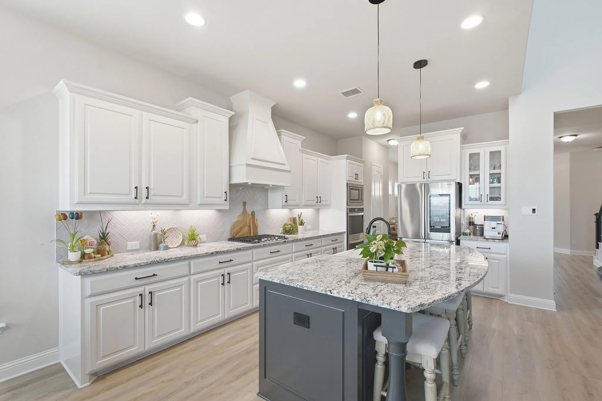 Modern kitchen featuring white cabinetry, a large kitchen island with a stone countertop, stainless steel appliances, and wood-finish flooring