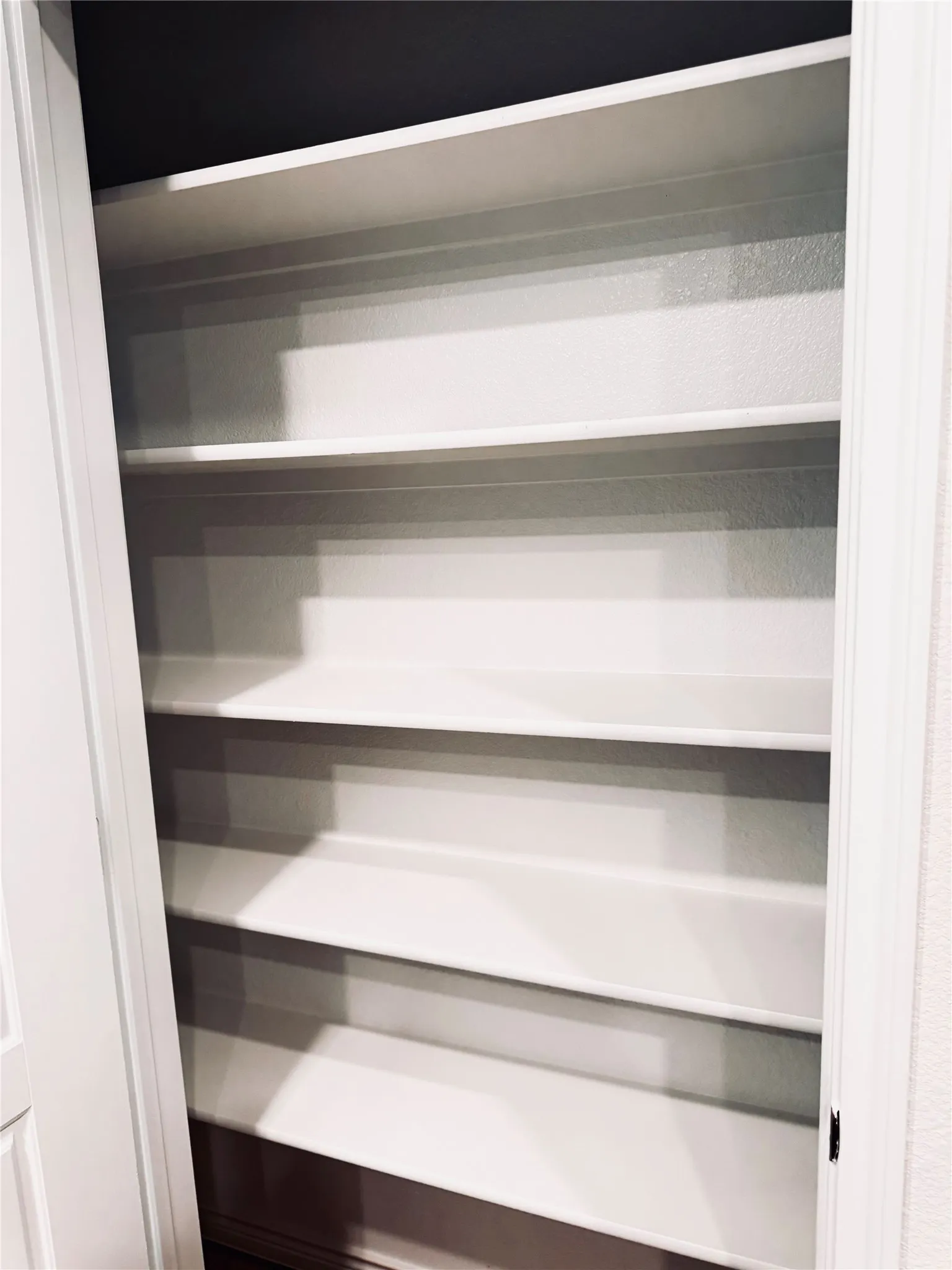Built-in shelving unit featuring multiple white shelves and a dark background