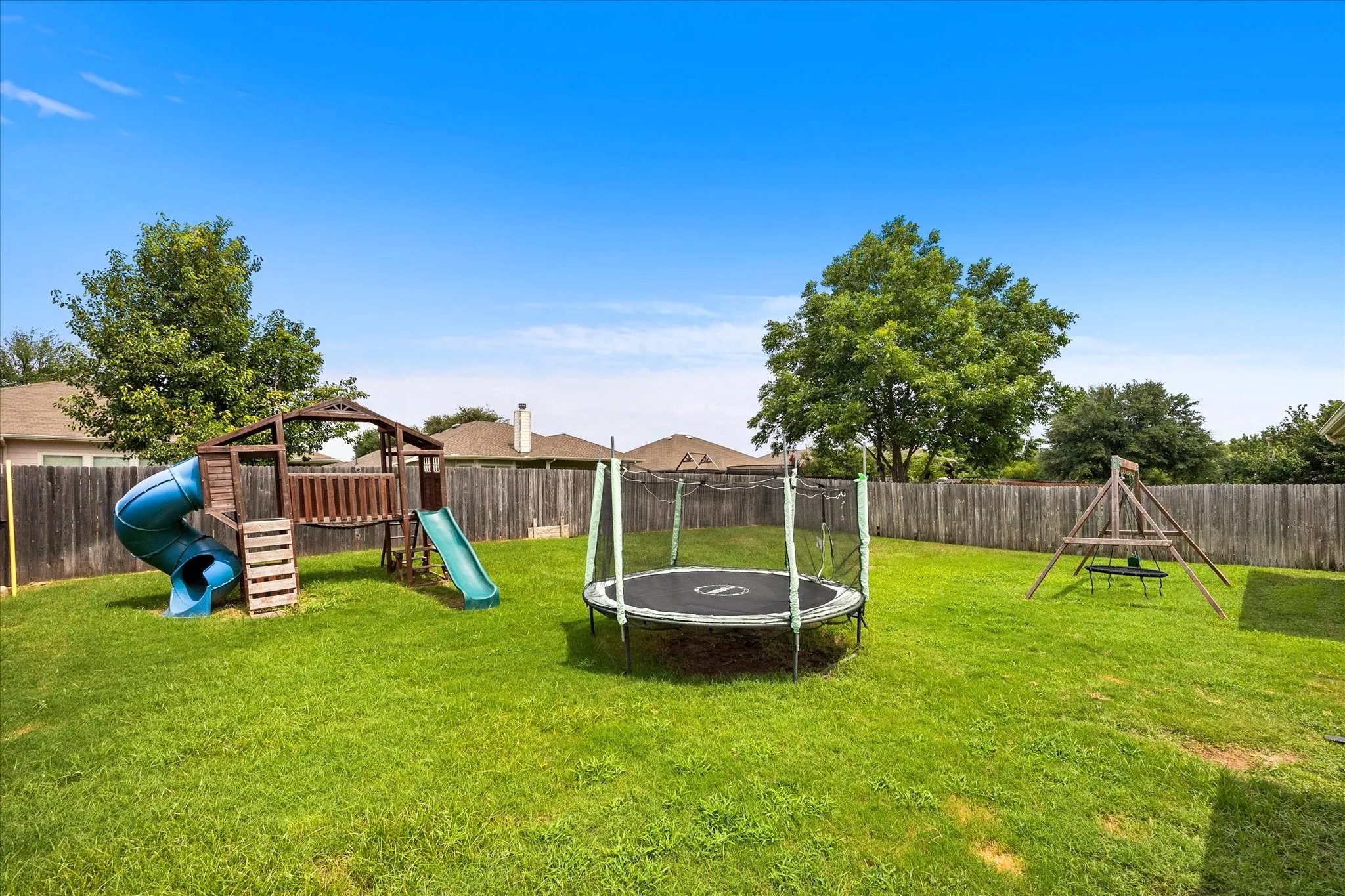 Spacious fenced backyard featuring a substantial green lawn