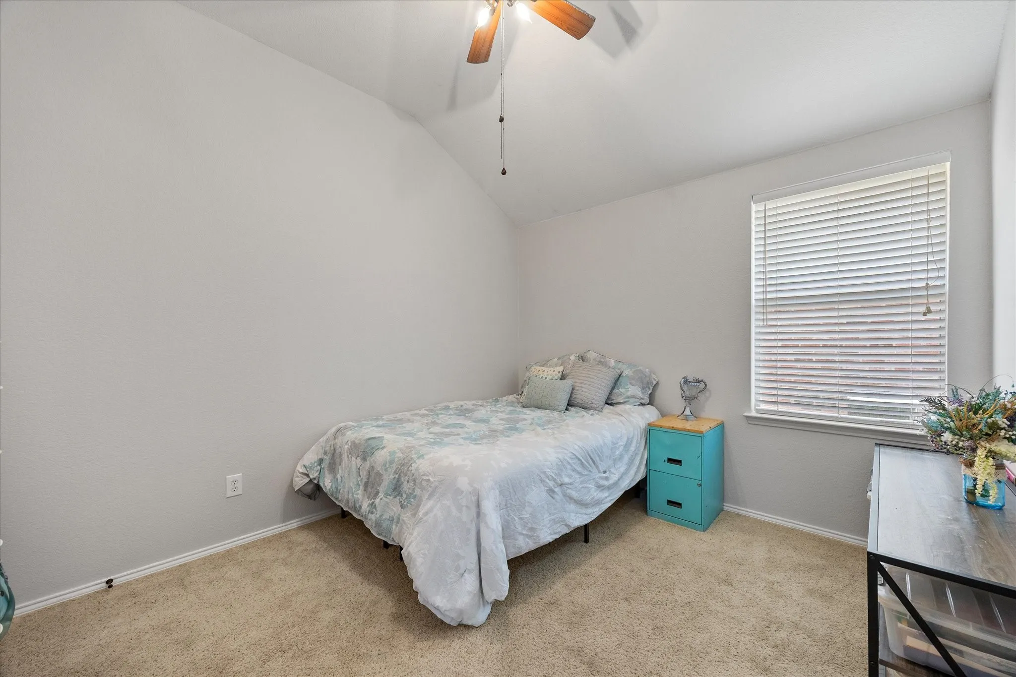 Carpeted bedroom featuring a vaulted ceiling and a ceiling fan