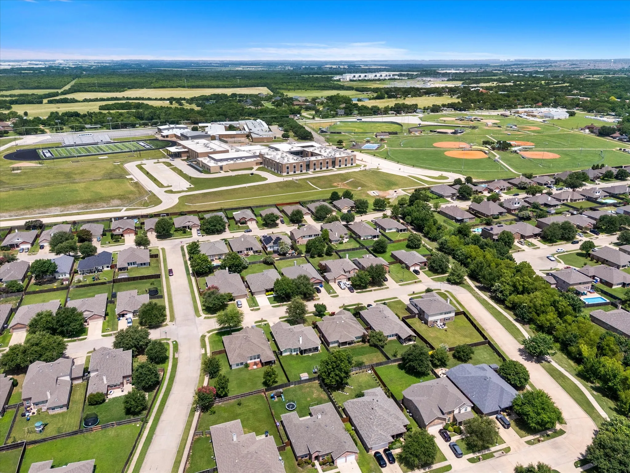 Aerial perspective showcasing a residential neighborhood with single-story homes, green lawns, and mature trees