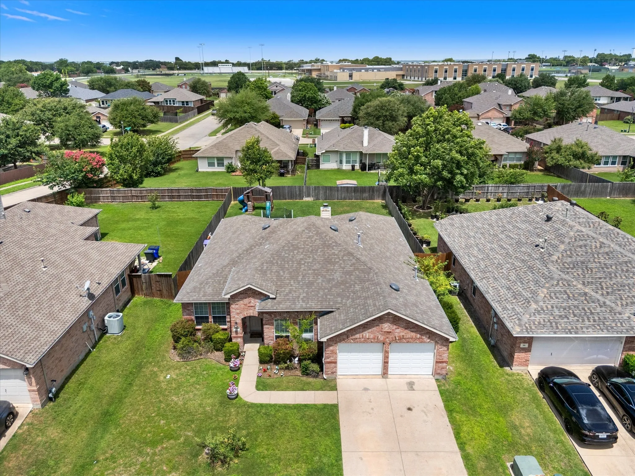Brick exterior residence featuring an attached two-car garage, concrete driveway, and a well-maintained front lawn