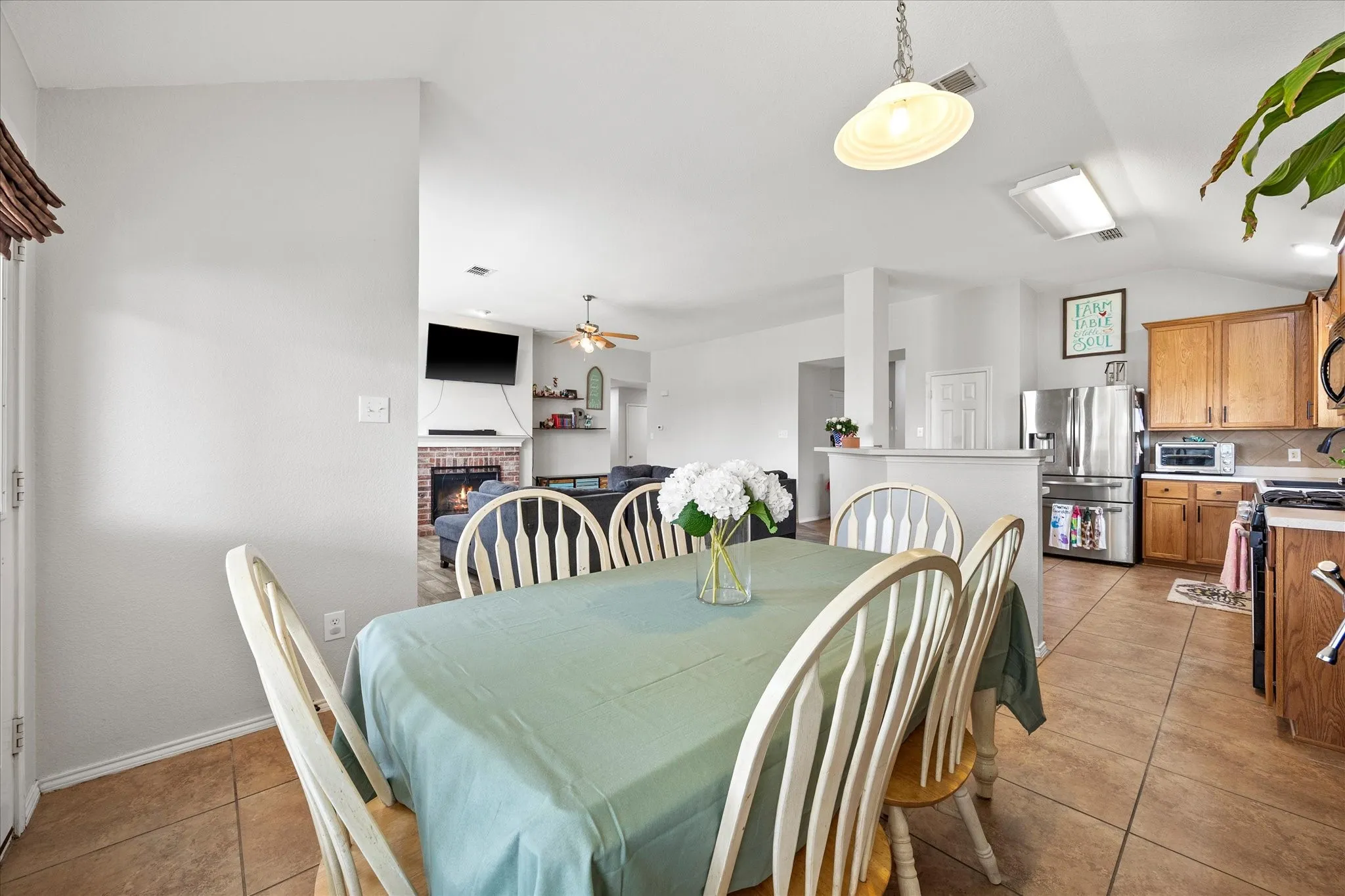 Open-concept interior featuring tile flooring, vaulted ceilings, and a kitchen with warm-toned cabinetry