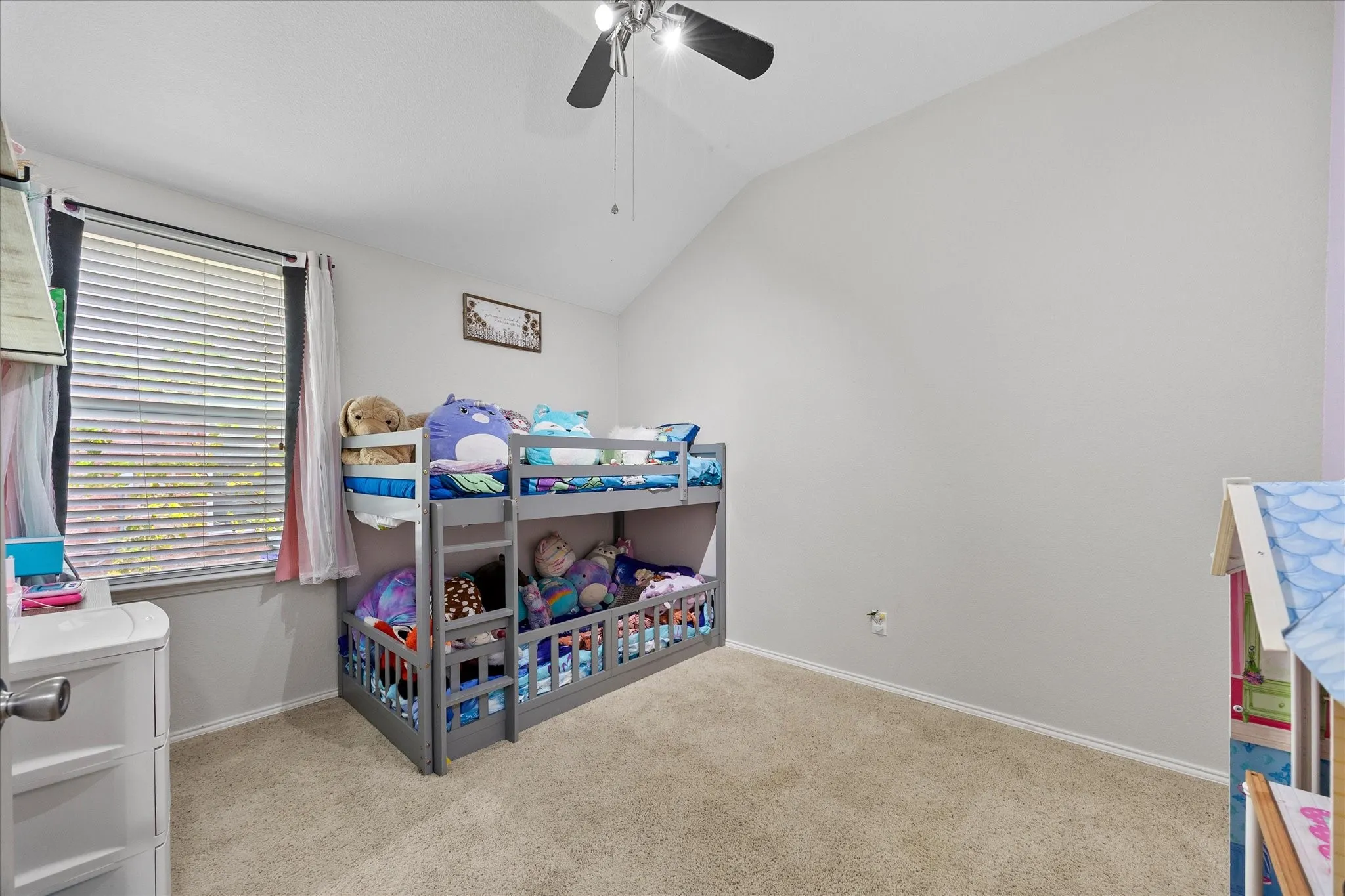 Carpeted room featuring a vaulted ceiling and a ceiling fan with light fixture