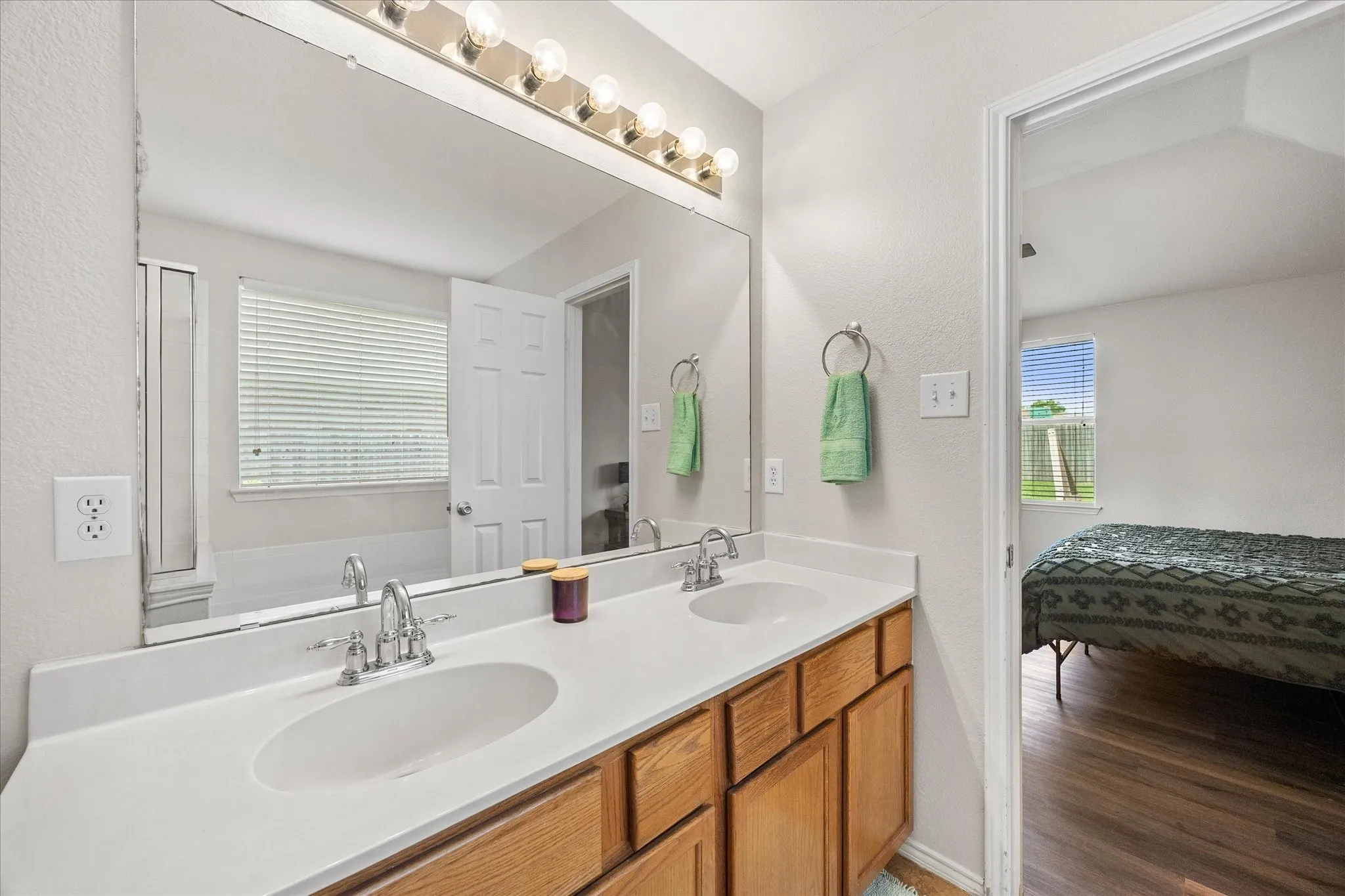 Bathroom vanity featuring double sinks with chrome faucets, a full-width mirror, and a five-light vanity fixture