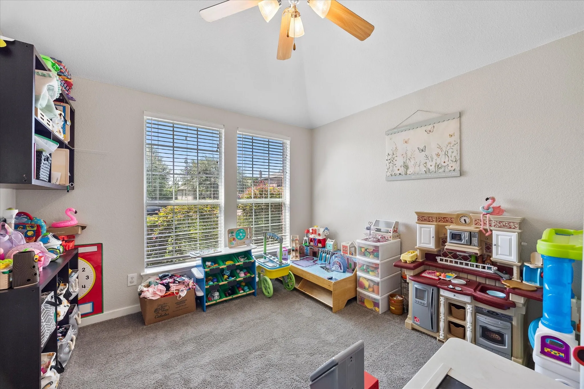 Room featuring neutral wall tones, carpet flooring, a ceiling fan, and two windows with blinds