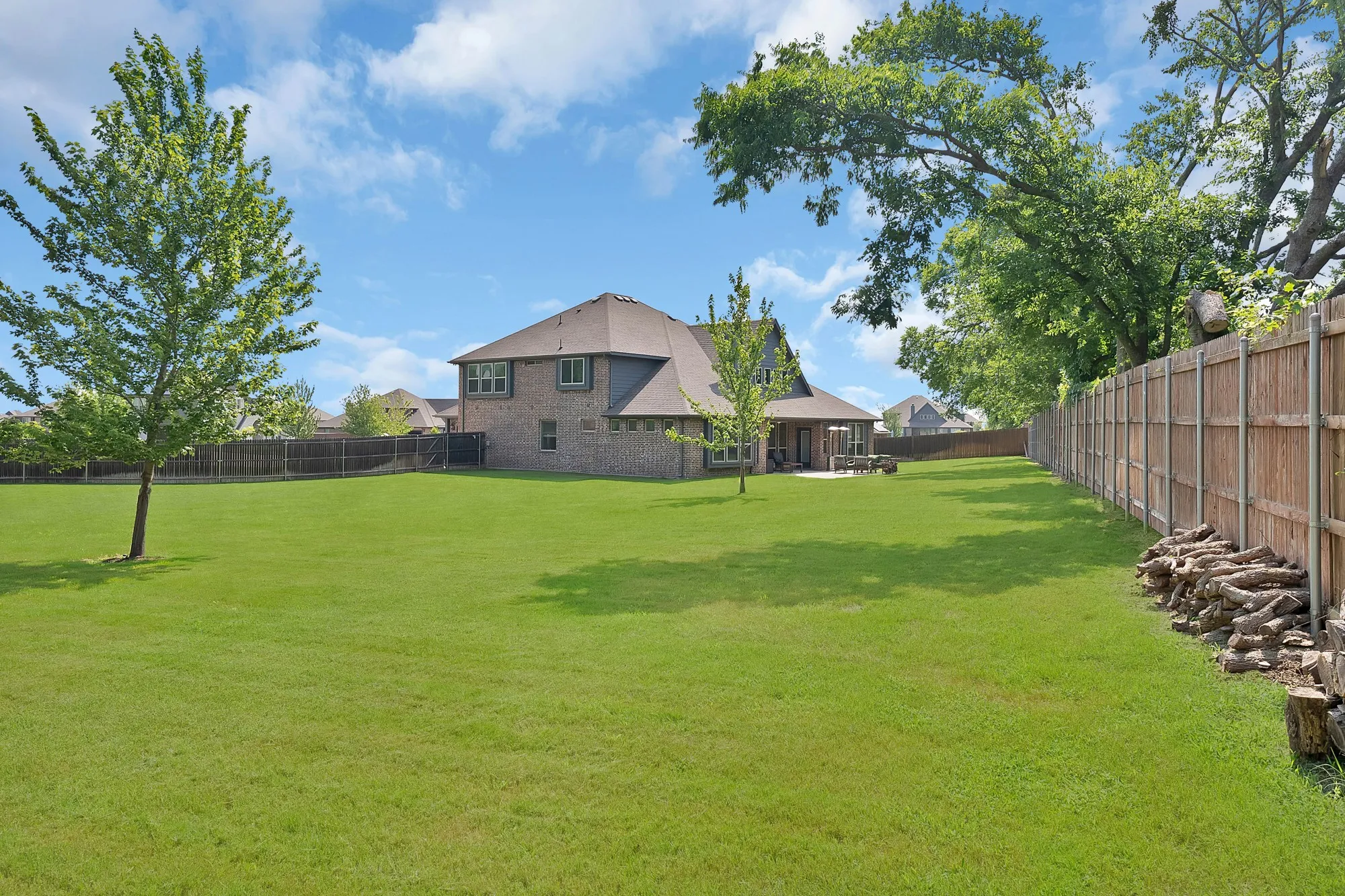 Expansive green lawn with mature trees and a private wooden perimeter fence