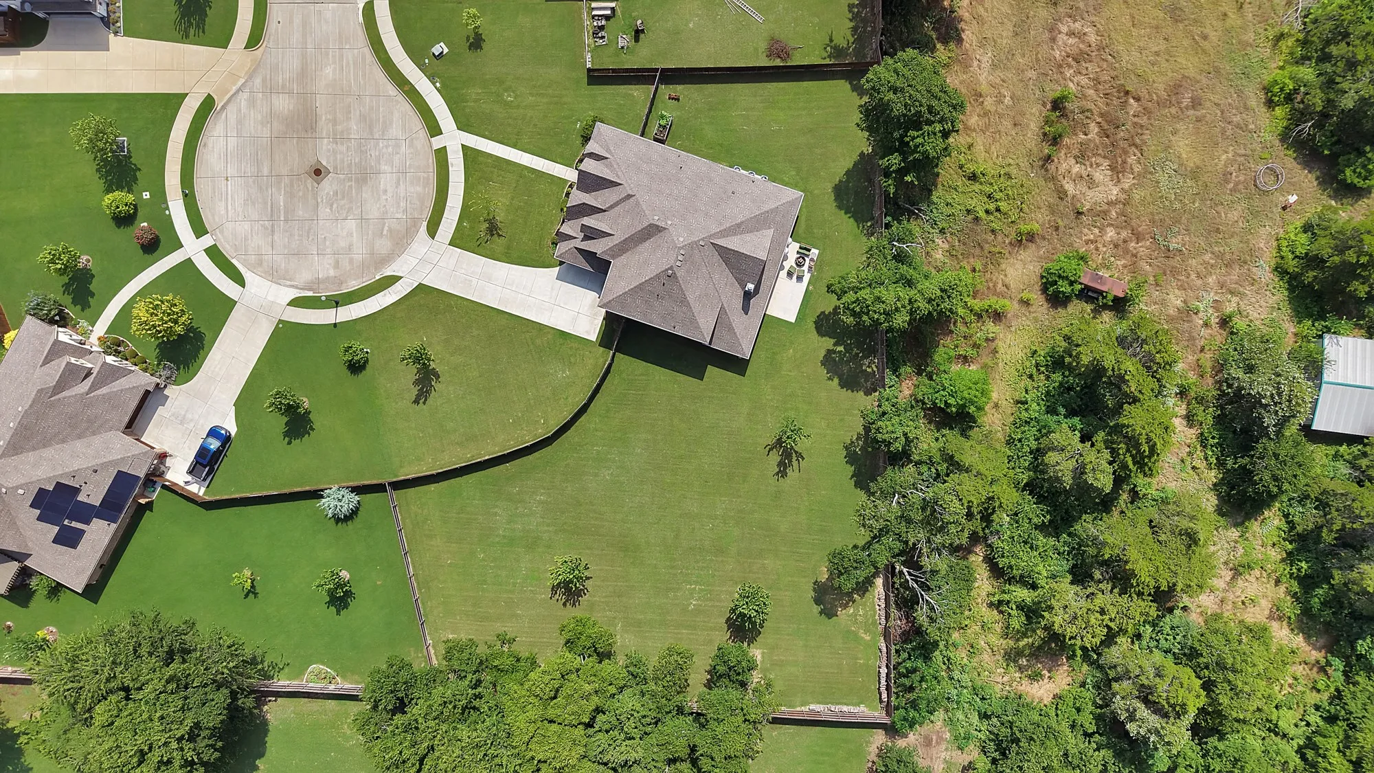 Expansive property featuring a well-maintained lawn, mature trees, and a concrete driveway