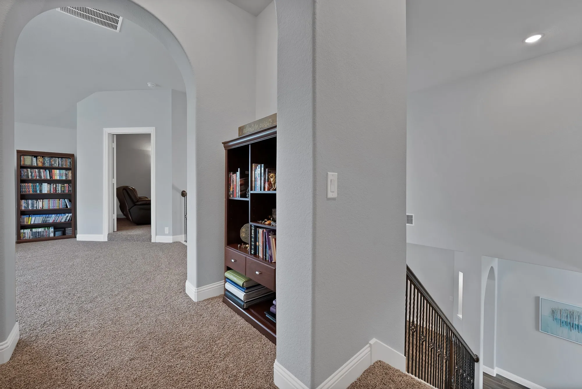 Upper-level hallway featuring arched doorways, light gray wall paint, and plush carpeting