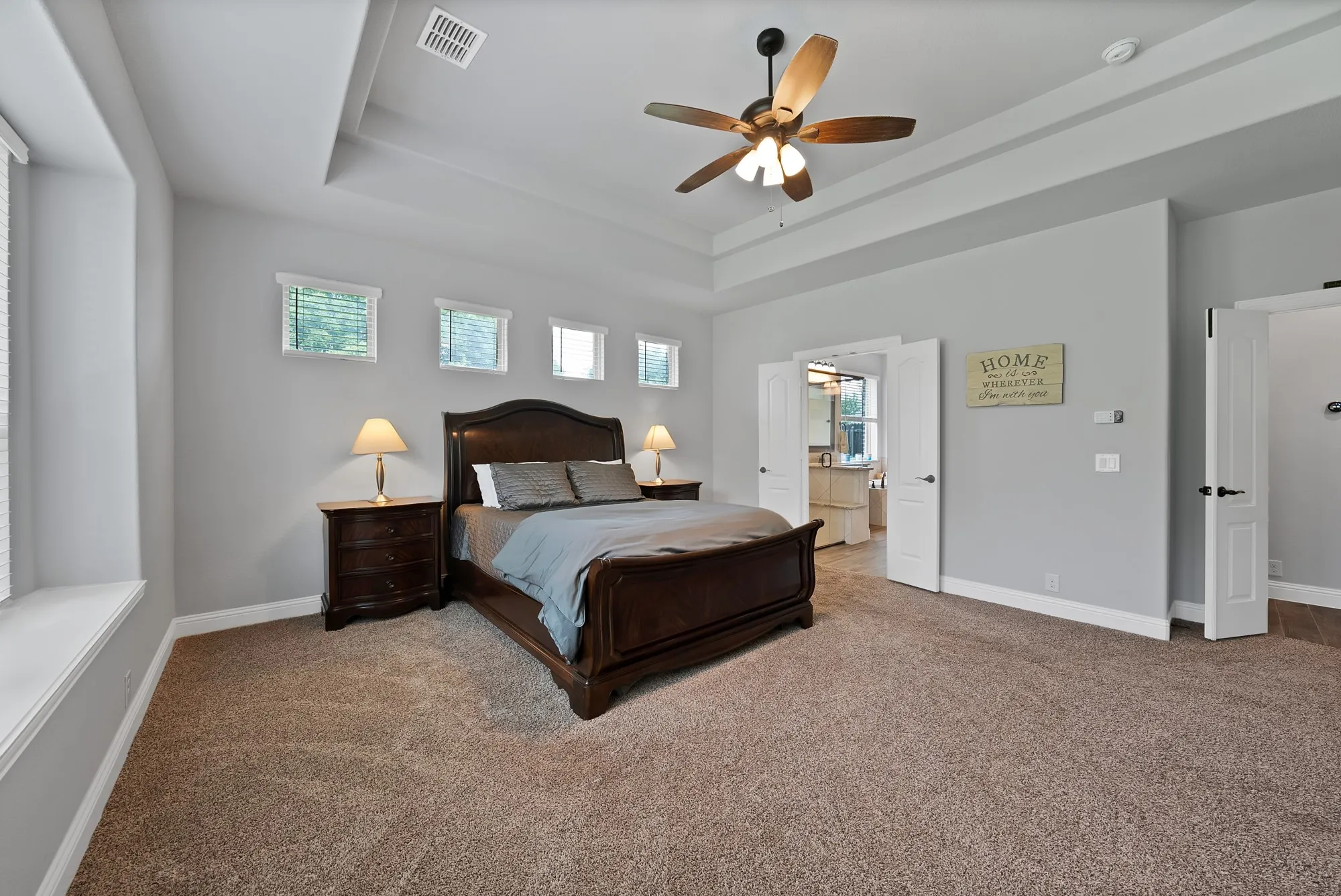Spacious room featuring tray ceiling, ceiling fan, neutral wall paint, and plush carpeting