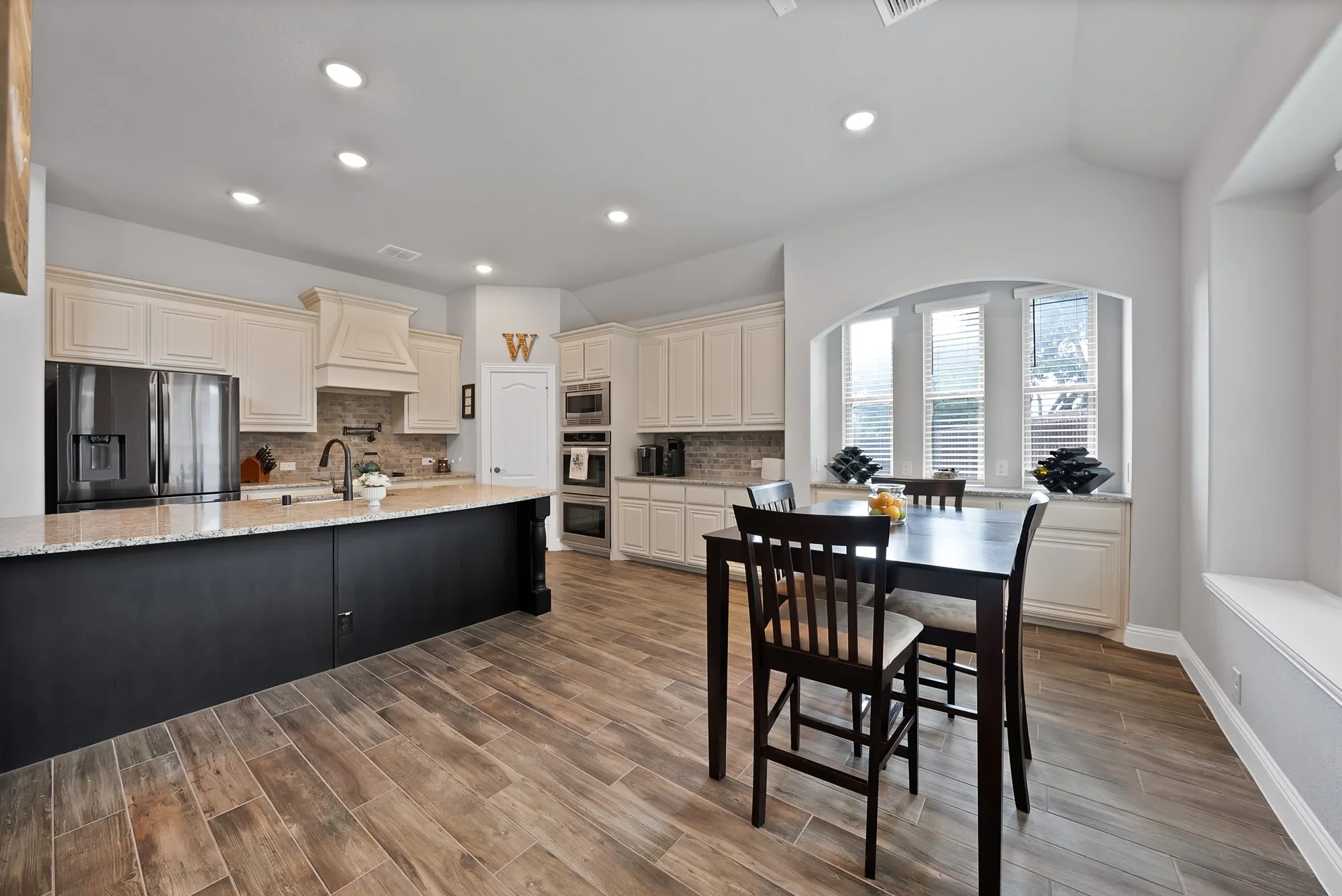 Spacious kitchen featuring wood-finish flooring, recessed lighting, and an expansive island with a light-colored countertop