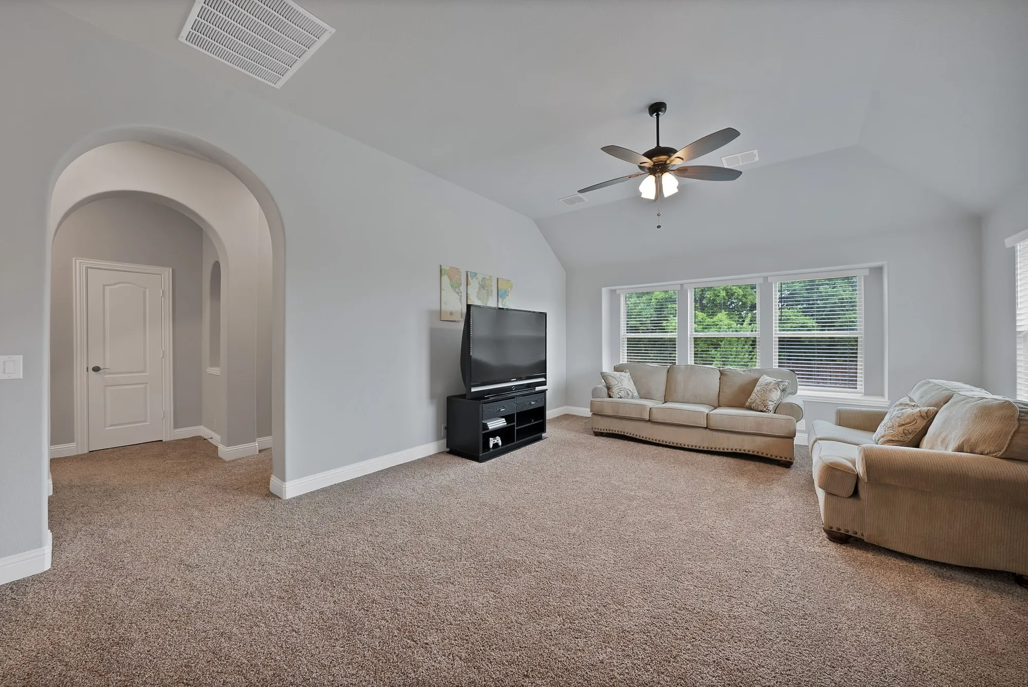 Spacious living area featuring neutral carpeting and light gray walls
