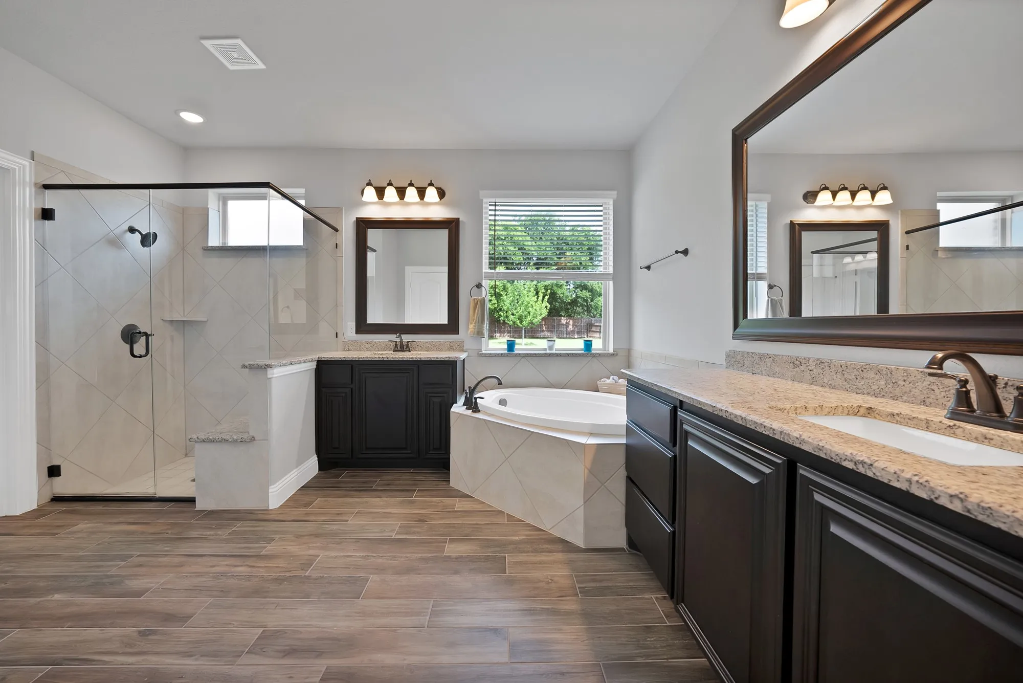 Spacious bathroom featuring wood-finish flooring, a corner soaking tub, and a separate glass-enclosed shower