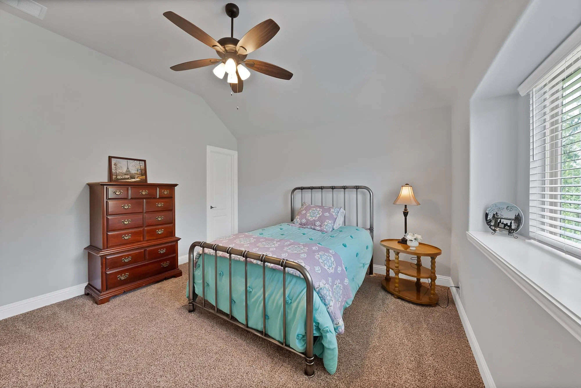 Carpeted room featuring a ceiling fan with integrated lighting, a white paneled door, and a window with white blinds
