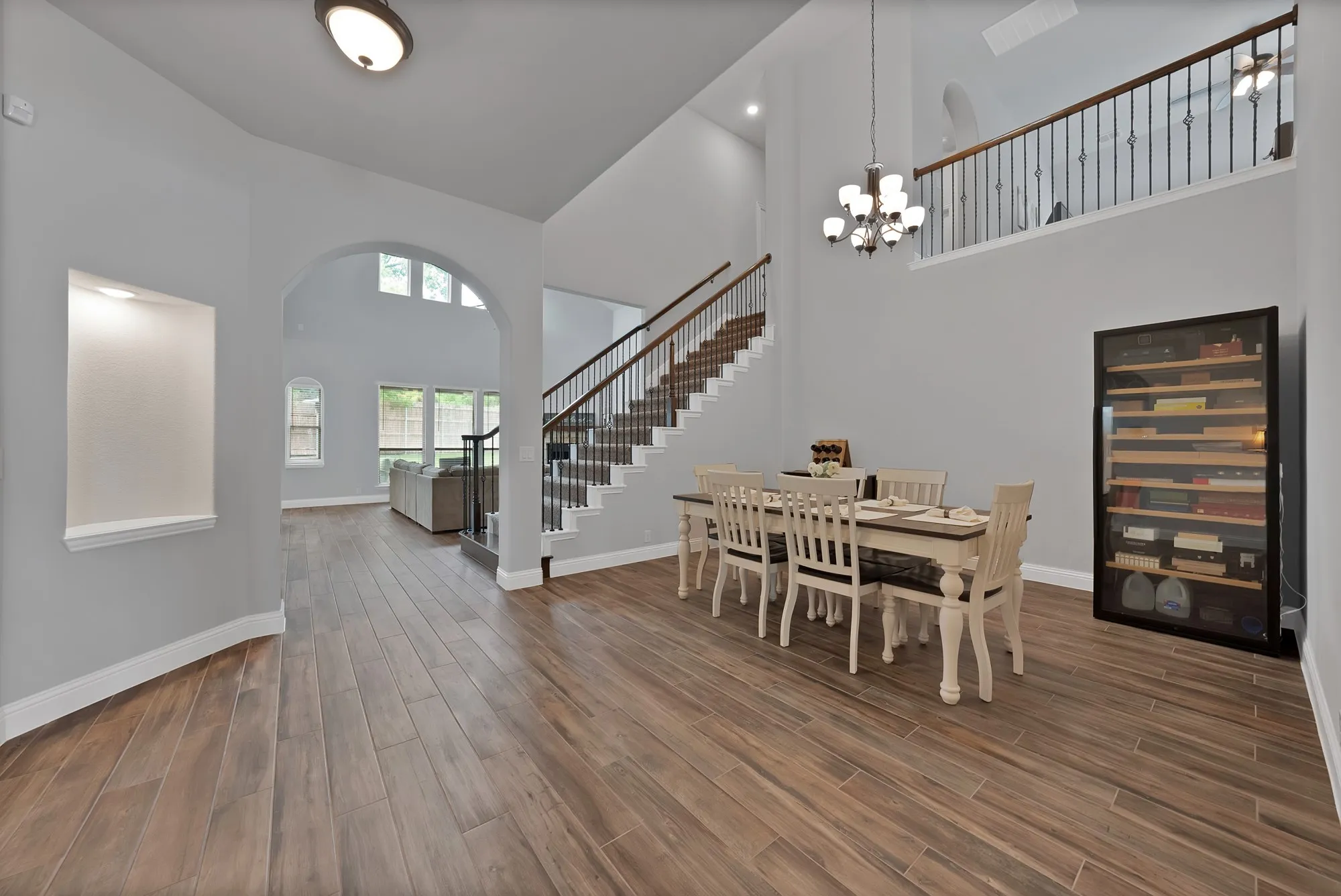 Spacious interior featuring wood-finish flooring, a two-story ceiling, and an archway leading to additional living areas