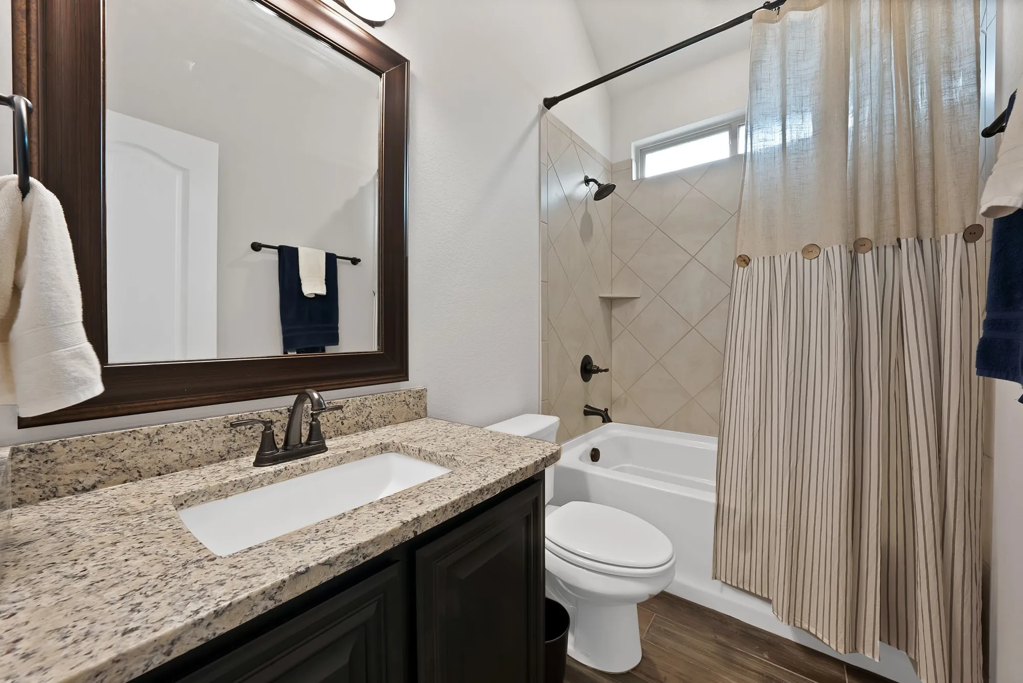 Bathroom featuring a vanity with a granite-style countertop, dark wood-finish cabinetry, and an undermount sink