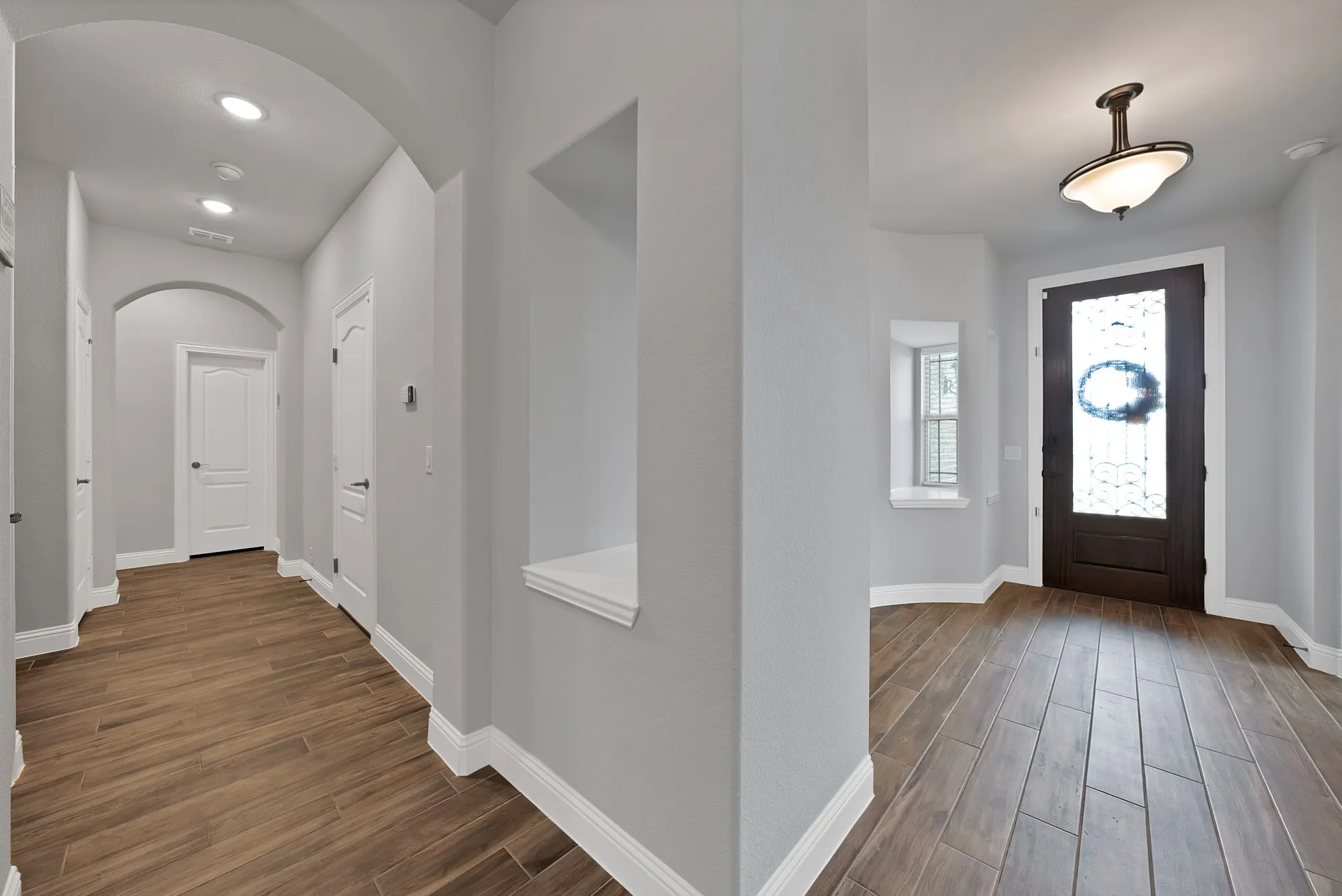Foyer entry with wood-finish flooring, dark wood door featuring decorative glass, and a semi-flush mount ceiling fixture