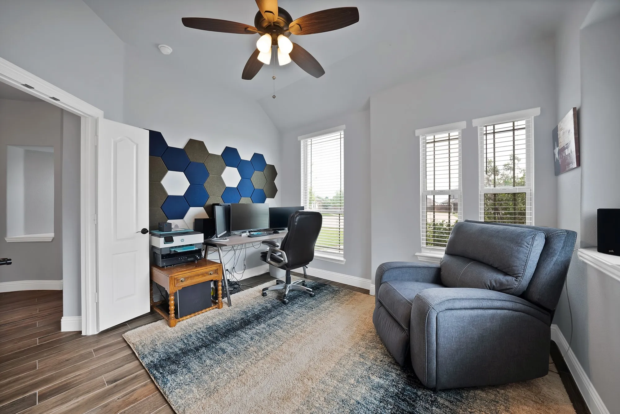Room featuring wood-finish flooring, vaulted ceiling, and multiple windows with blinds