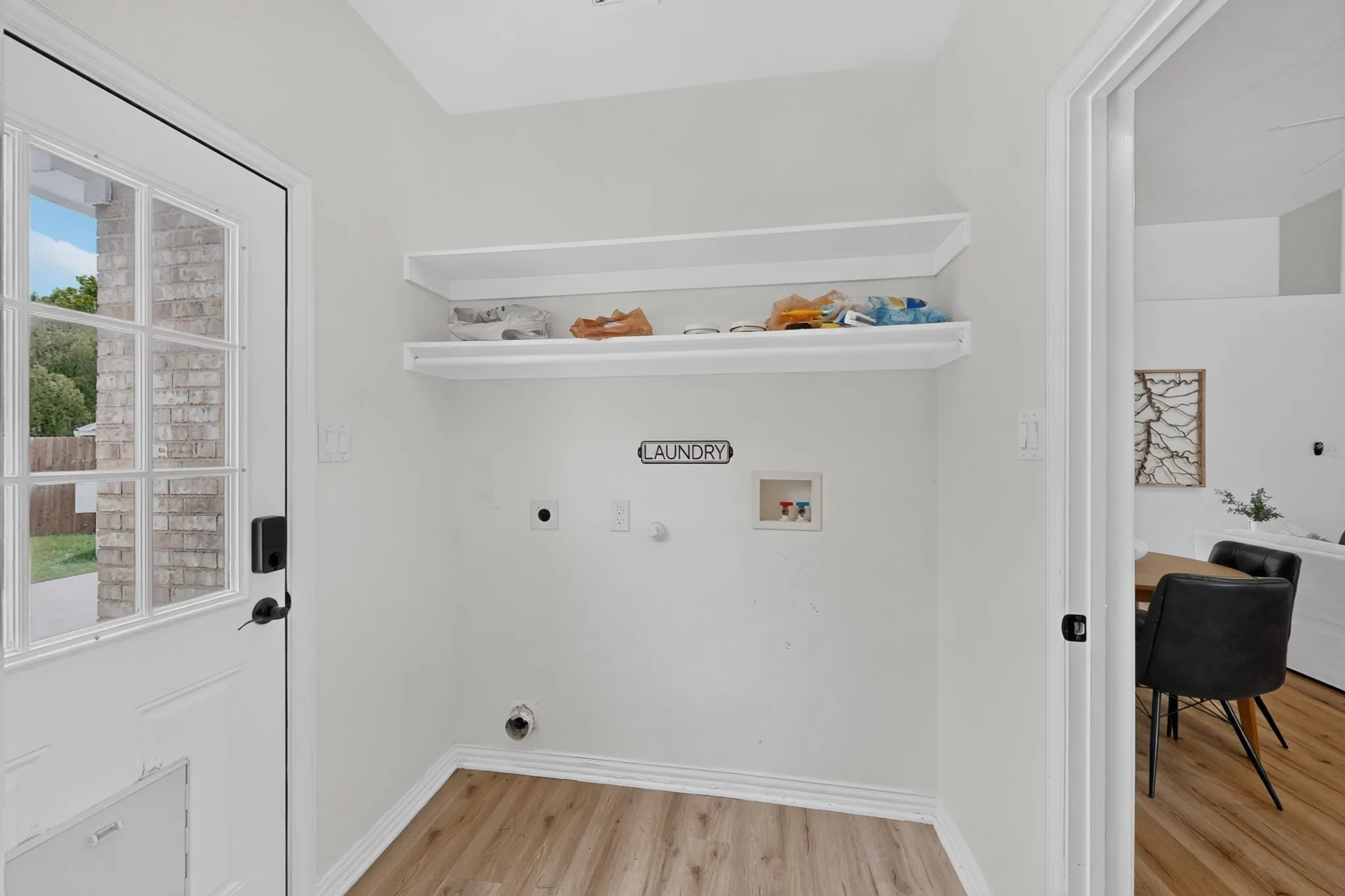 Dedicated laundry area featuring wood-finish flooring, white walls, and built-in shelving