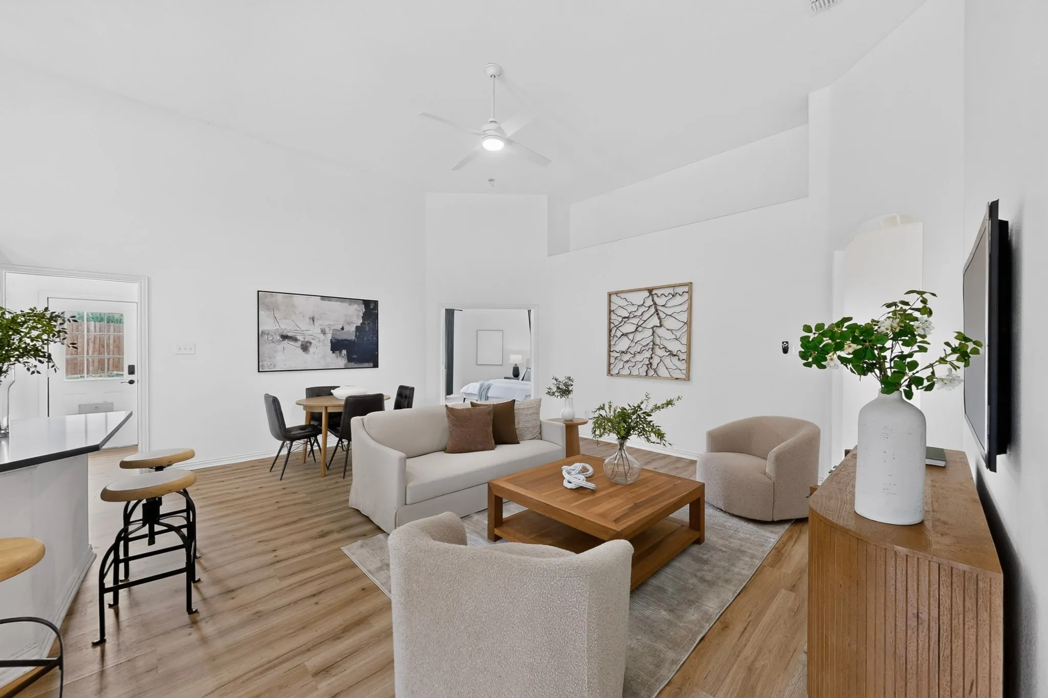 Open-concept living area featuring wood-finish flooring, vaulted ceilings, and a ceiling fan