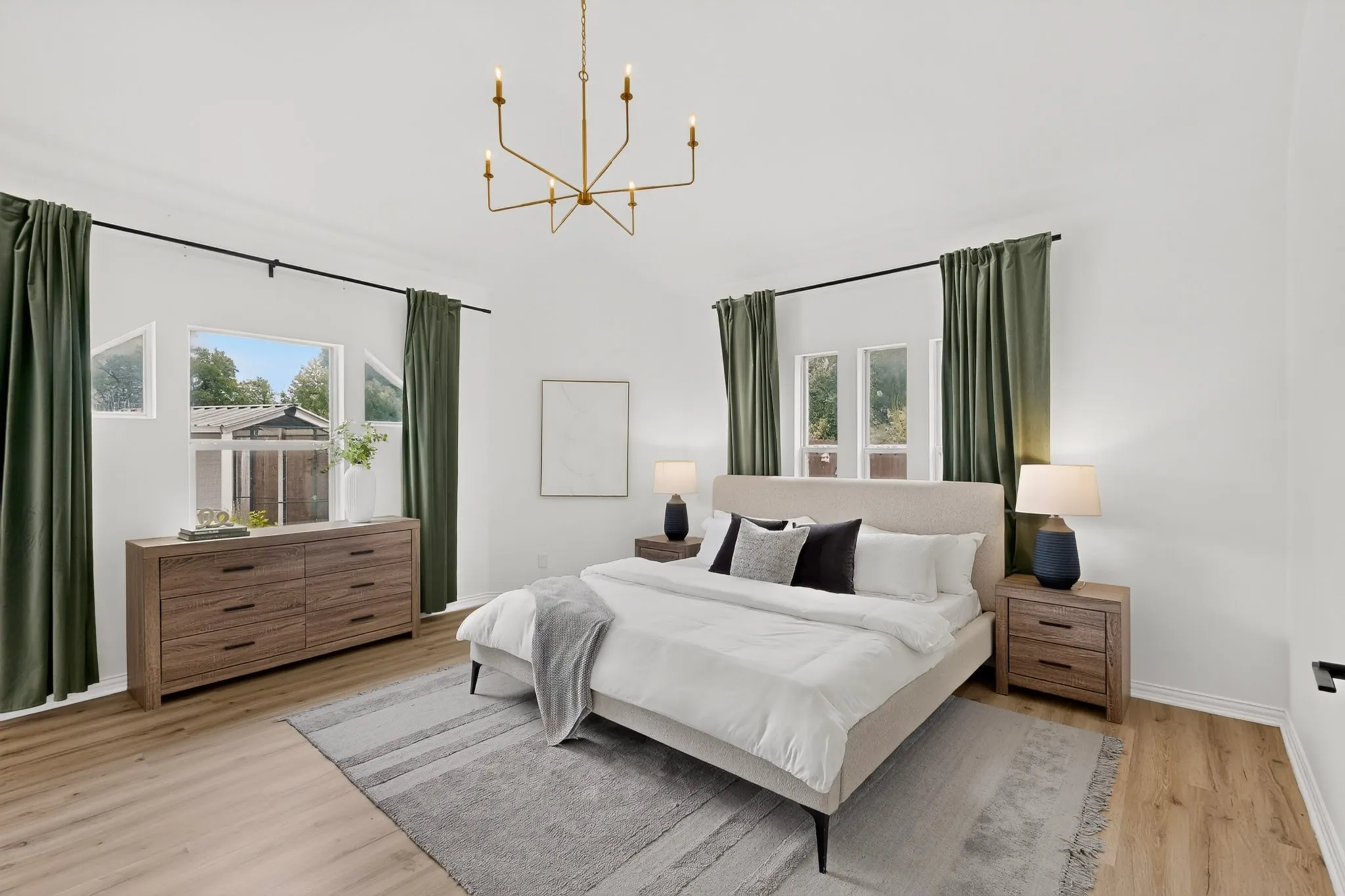 Bright bedroom featuring light wood-finish flooring, a modern chandelier, and white walls
