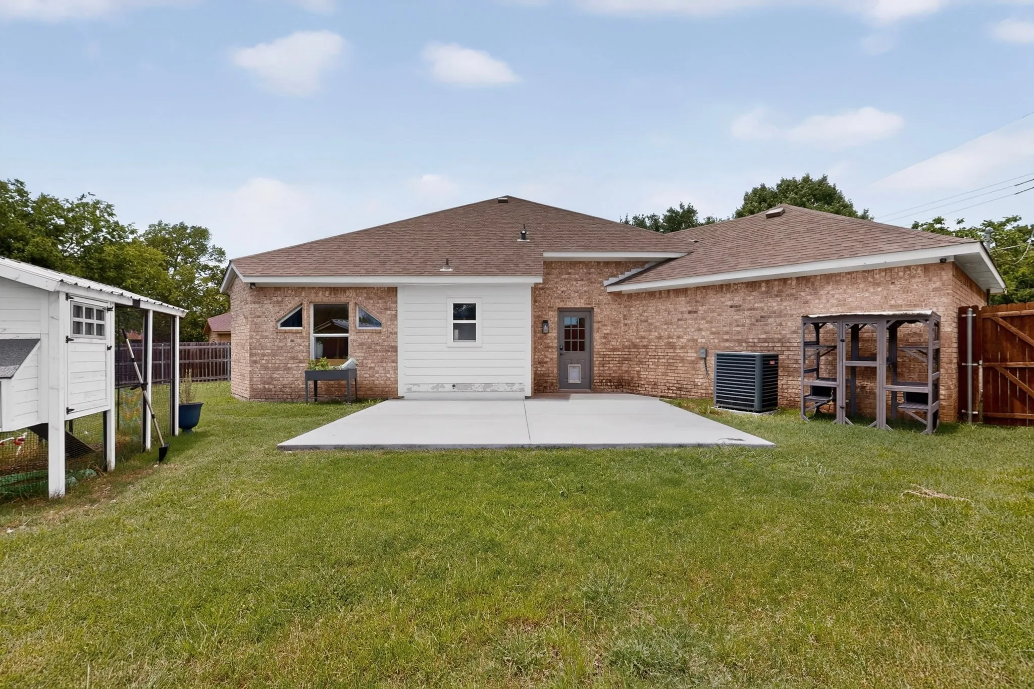 Rear exterior featuring brick and horizontal siding, a concrete patio, and a fenced yard