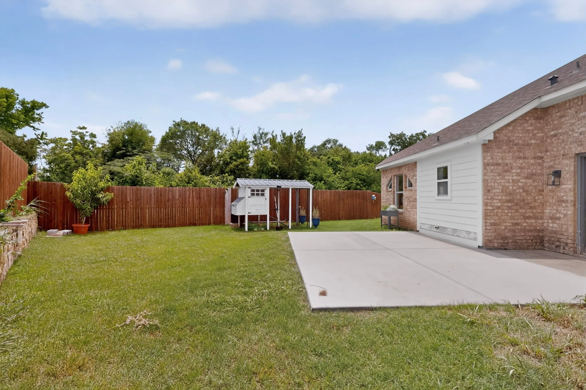 Expansive backyard featuring a manicured lawn, a large concrete patio, and a privacy fence