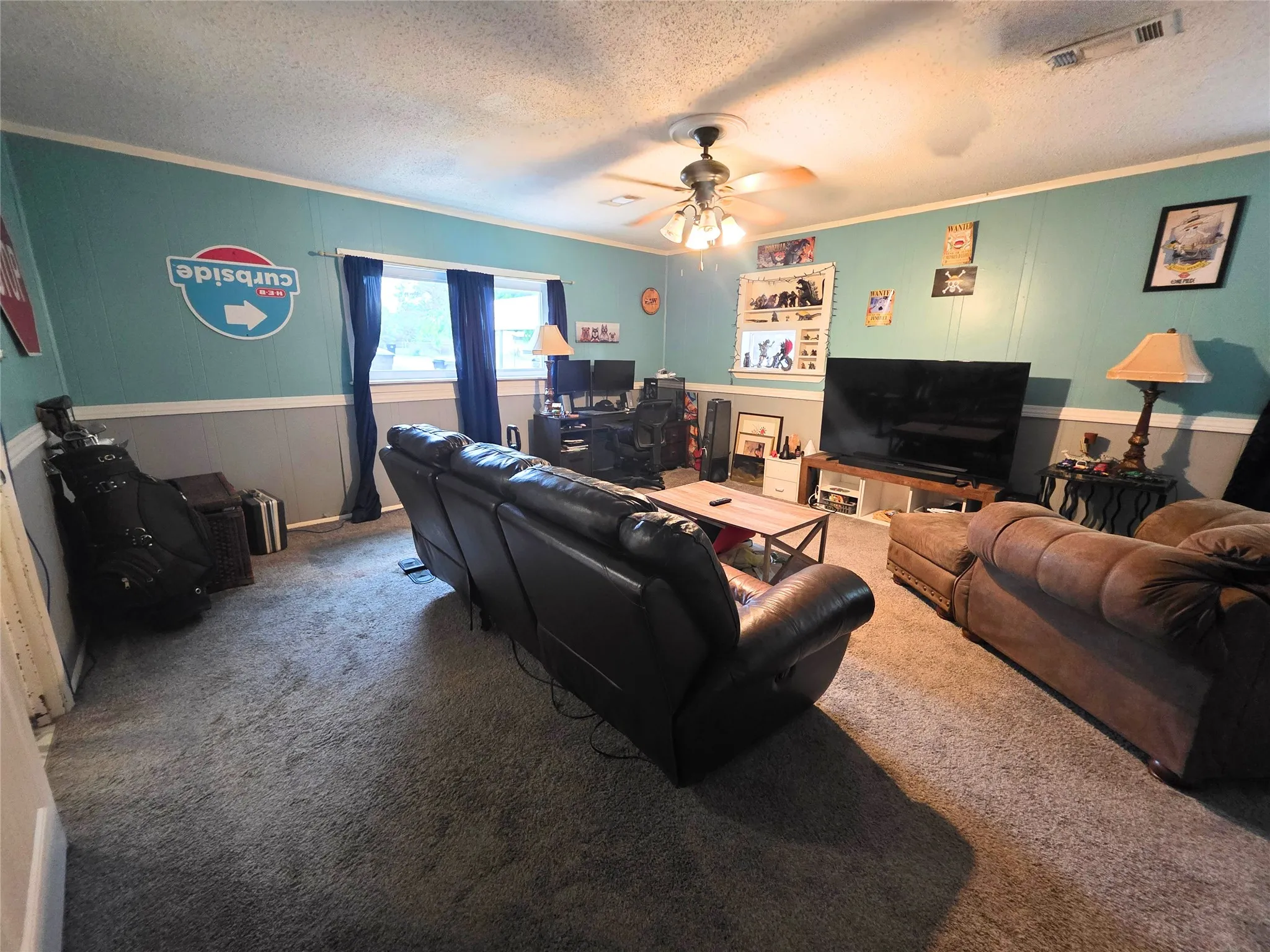 Interior room featuring light gray carpeting, two-tone walls with a lower gray paneling and upper teal section, and white crown molding