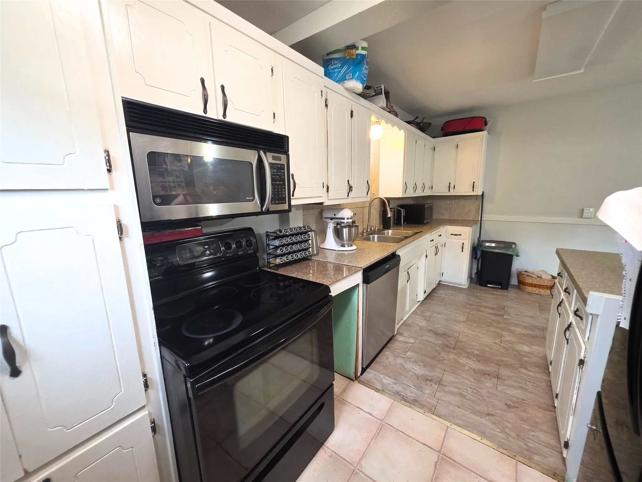 Kitchen featuring white cabinetry, a built-in stainless steel microwave, black electric range, stainless steel dishwasher, and a double basin sink with a gooseneck faucet