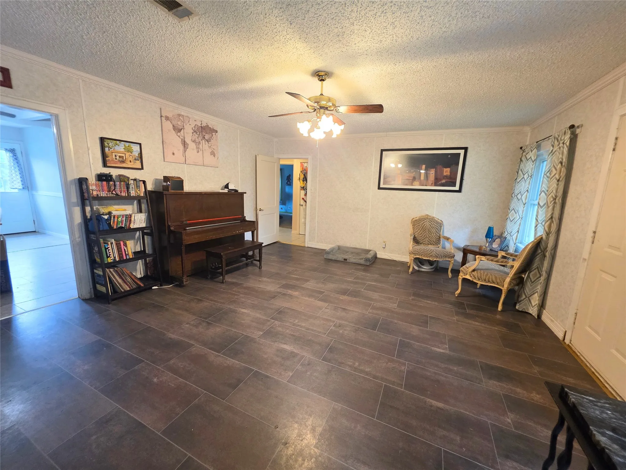 Spacious room featuring wood-finish flooring, textured wall panels, and a ceiling fan with light fixture