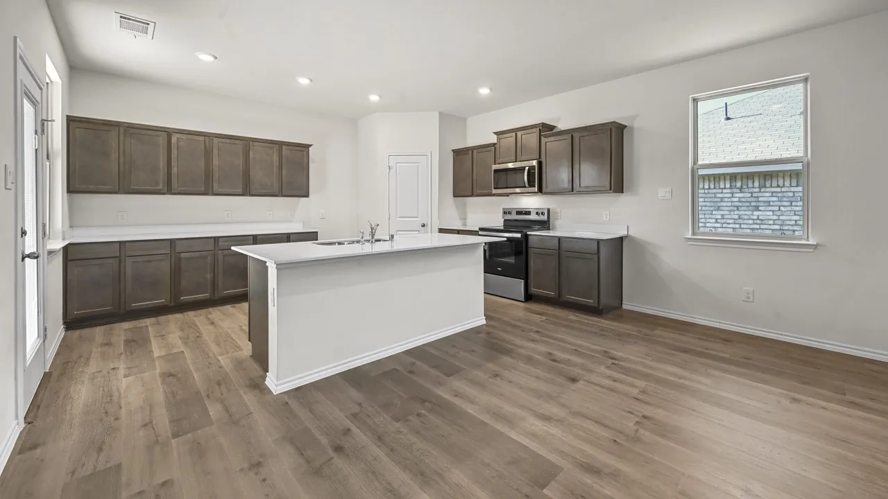 Open-concept kitchen featuring an island with a sink, dark wood-finish cabinetry, light-toned countertops, and wood-finish flooring