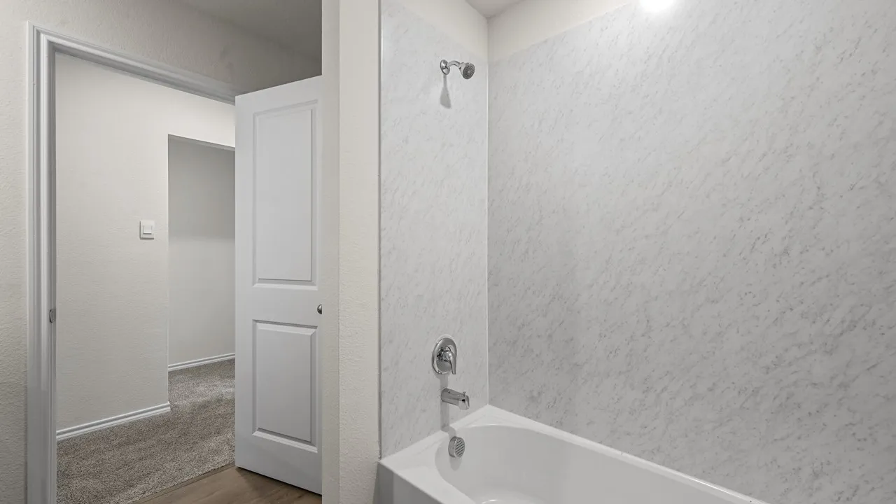 White bathtub and shower surround with a chrome showerhead and faucet