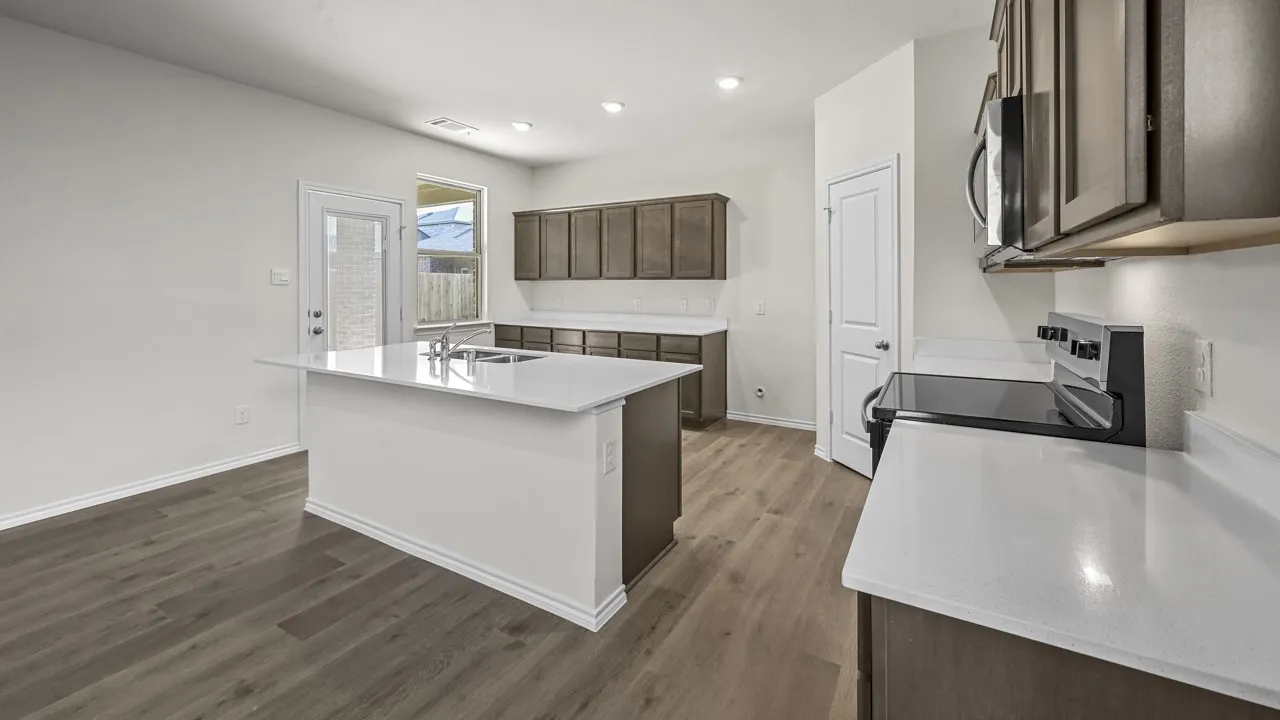 Spacious kitchen featuring an island, light wood-finish flooring, white countertops, dark wood cabinetry, and stainless steel appliances