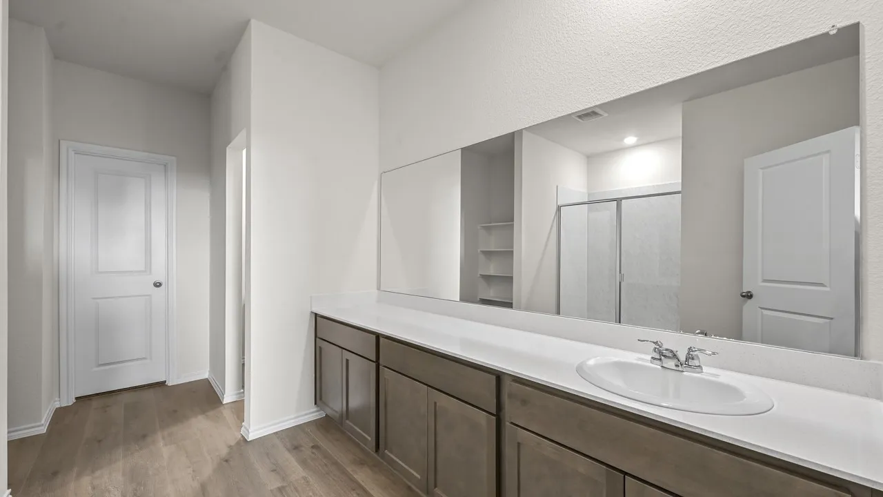 Bathroom vanity featuring a single integrated sink, chrome faucet, and expansive wall-mounted mirror