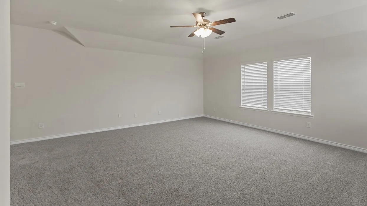 Spacious room featuring neutral carpeting, light-toned walls, and a ceiling fan with integrated lighting