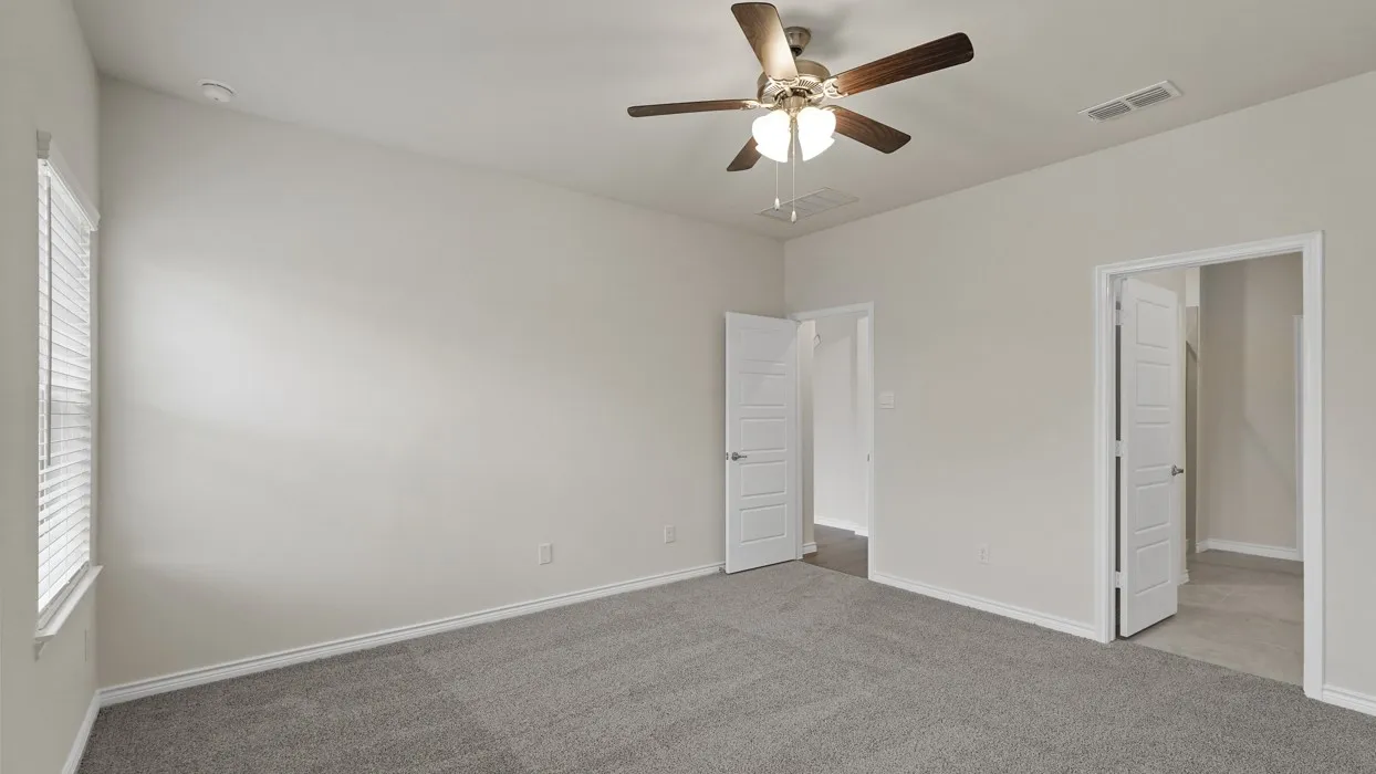 Spacious room featuring gray carpet flooring, light neutral-toned walls, and a ceiling fan with integrated lighting
