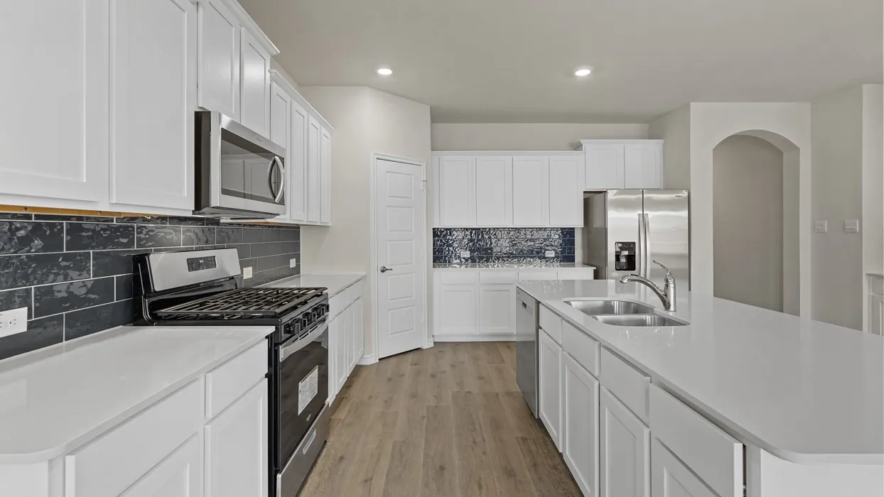 Expansive kitchen featuring white cabinetry, light countertops, wood-finish flooring, stainless steel appliances, and a dark subway tile backsplash