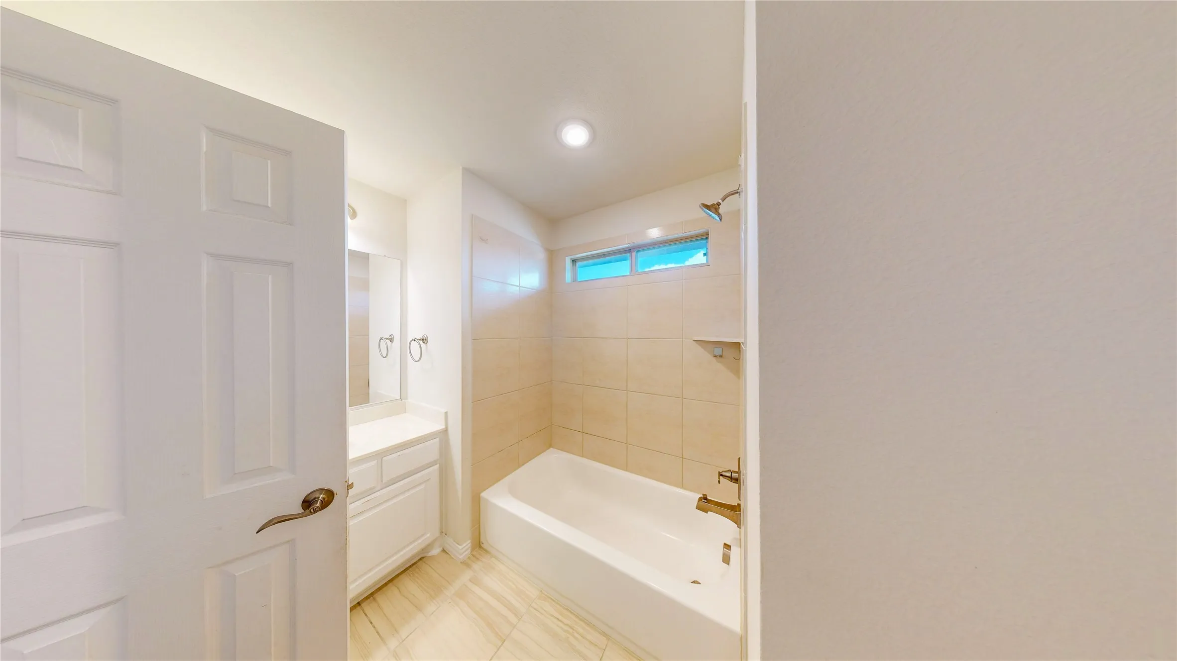 Bathroom featuring a built-in tub with tile surround, a single vanity with storage, and recessed lighting