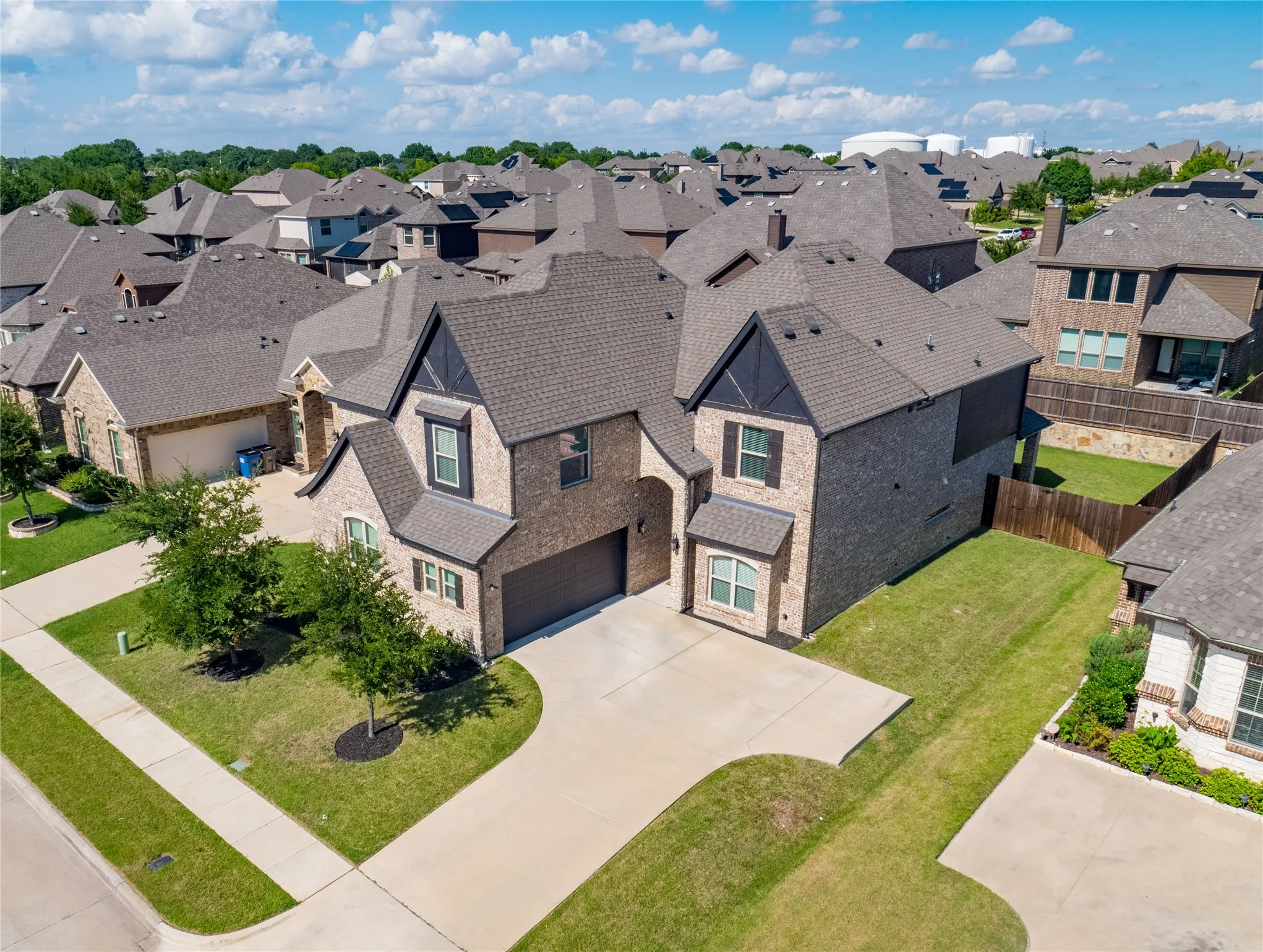 Brick and stone exterior residence featuring a two-car garage, concrete driveway, and front landscaping
