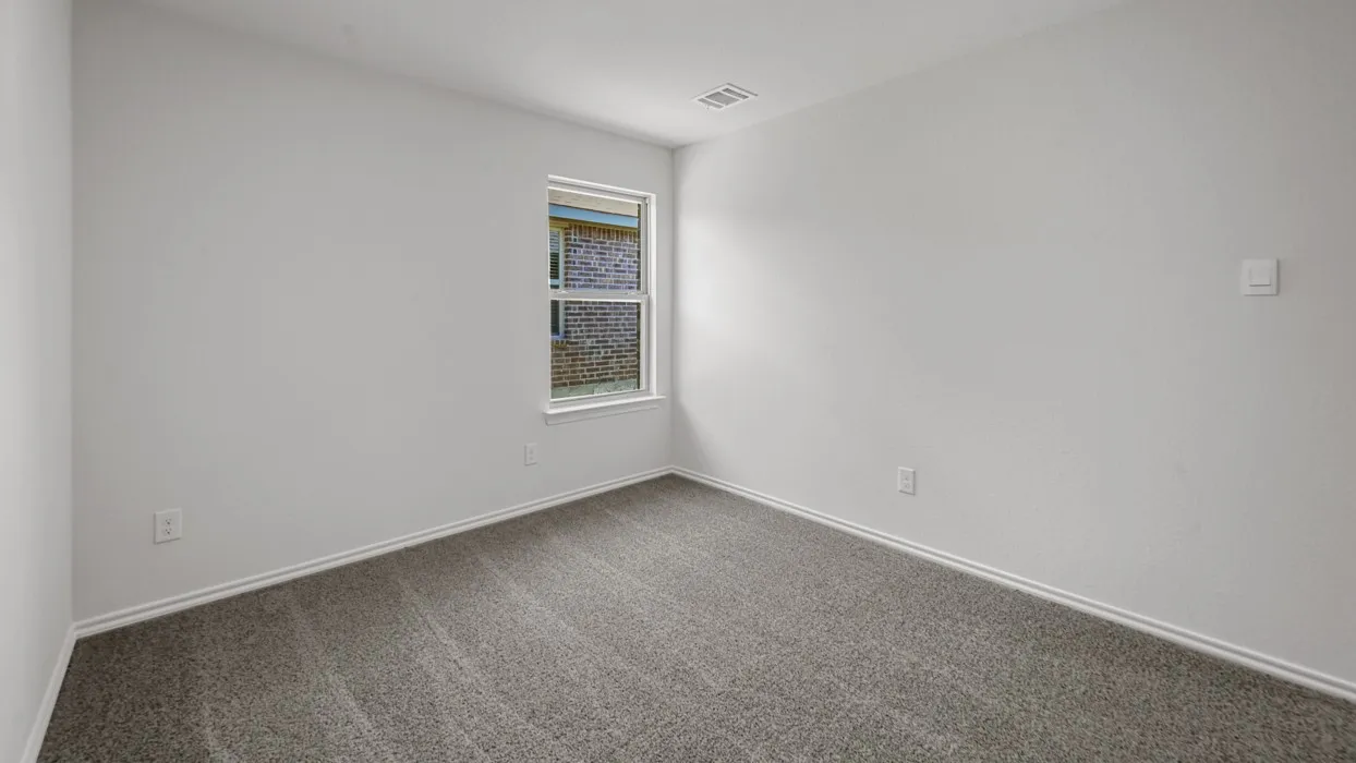 Neutral wall finishes with a window offering natural light, complemented by a gray carpet and white baseboards