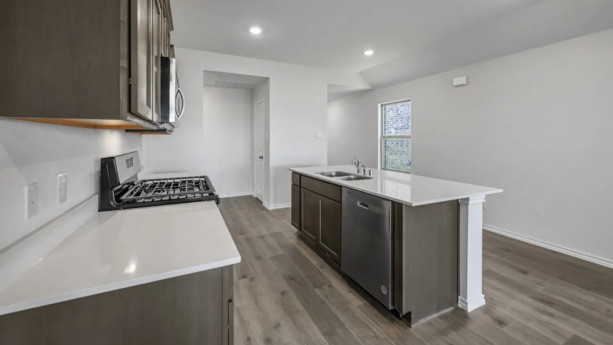 Open-concept kitchen featuring an island with built-in sink and stainless steel dishwasher