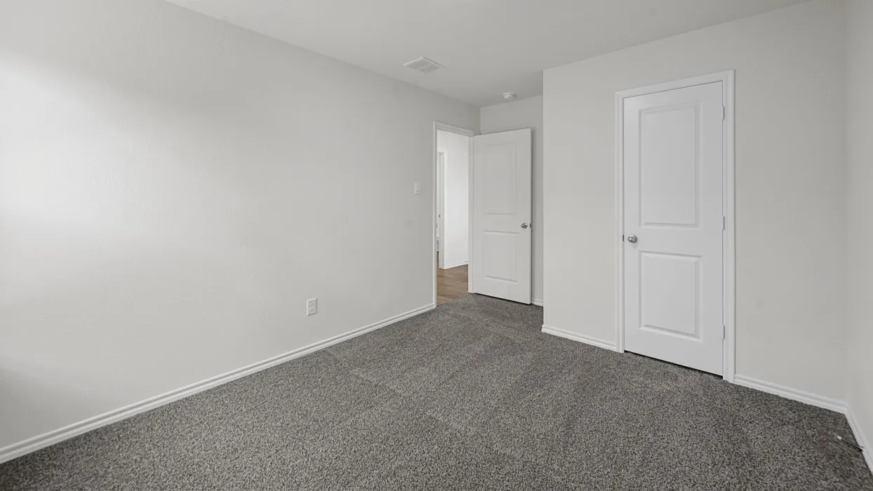 Carpeted room featuring white walls, white baseboards, and two paneled doors with chrome hardware