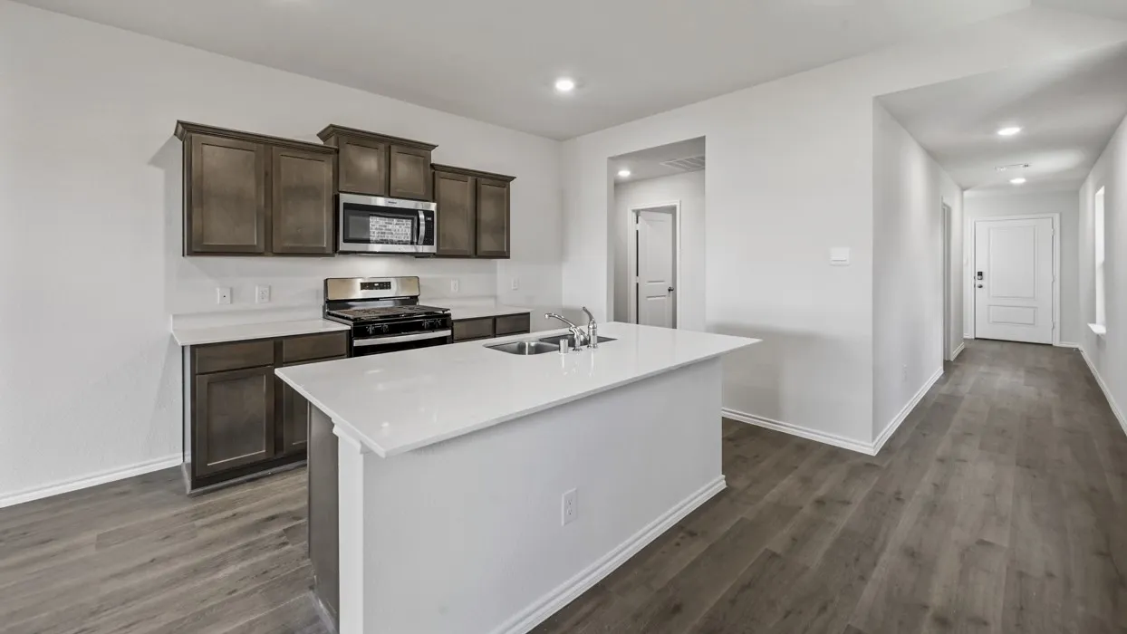 Modern kitchen featuring dark wood-finish cabinetry, light countertops, and a central island with an undermount double sink
