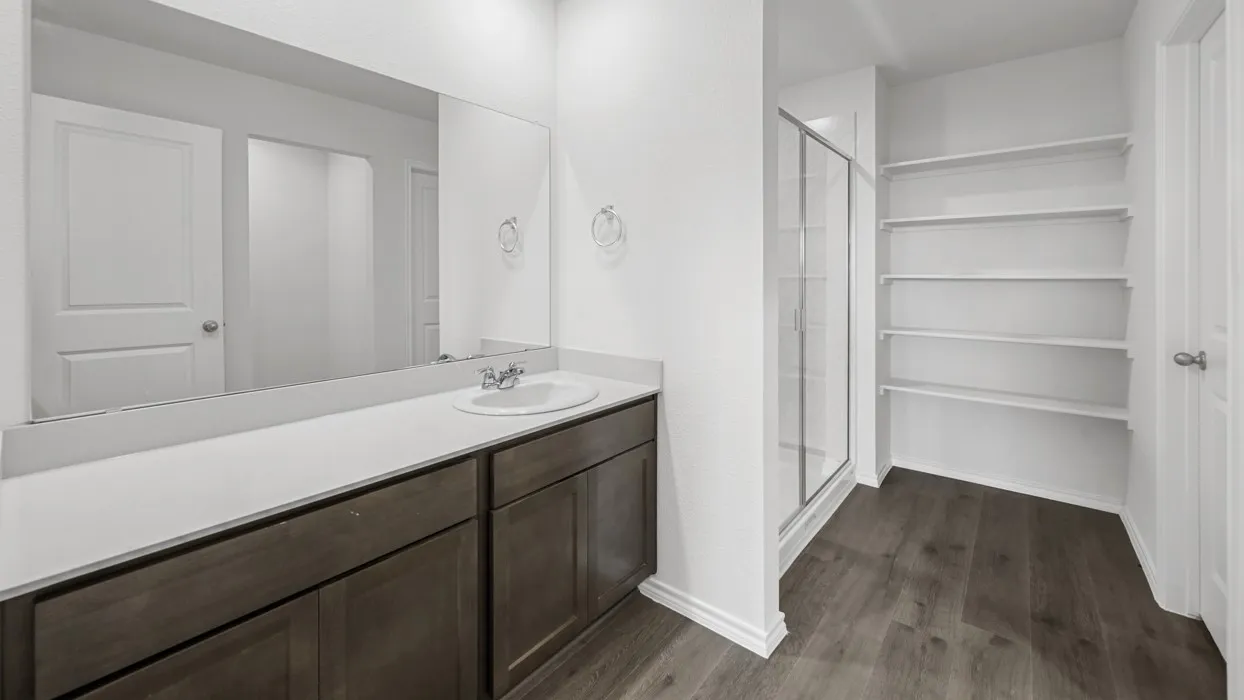 Bathroom vanity with a single sink, light-toned countertop, and dark wood-finish cabinetry