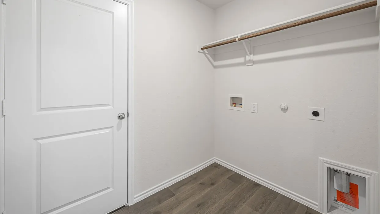 Utility space featuring light wood-finish flooring, white baseboards, and a white interior door with a chrome knob
