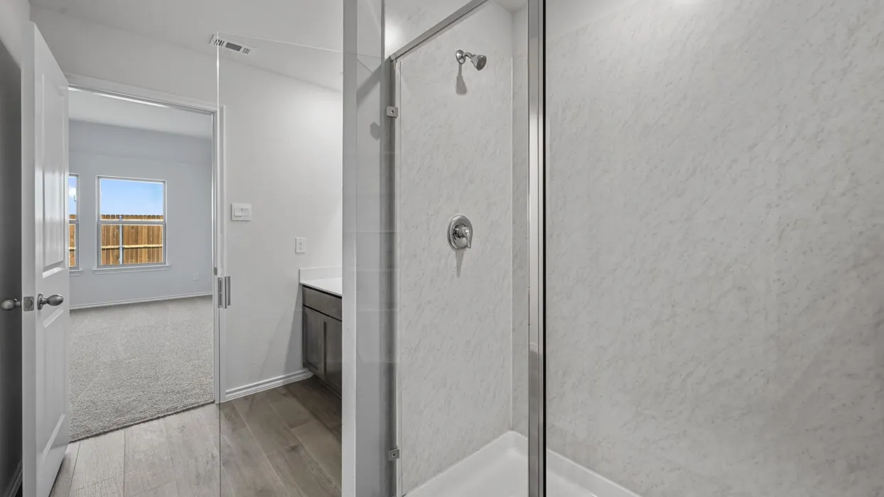 Glass-enclosed shower with a chrome showerhead and control