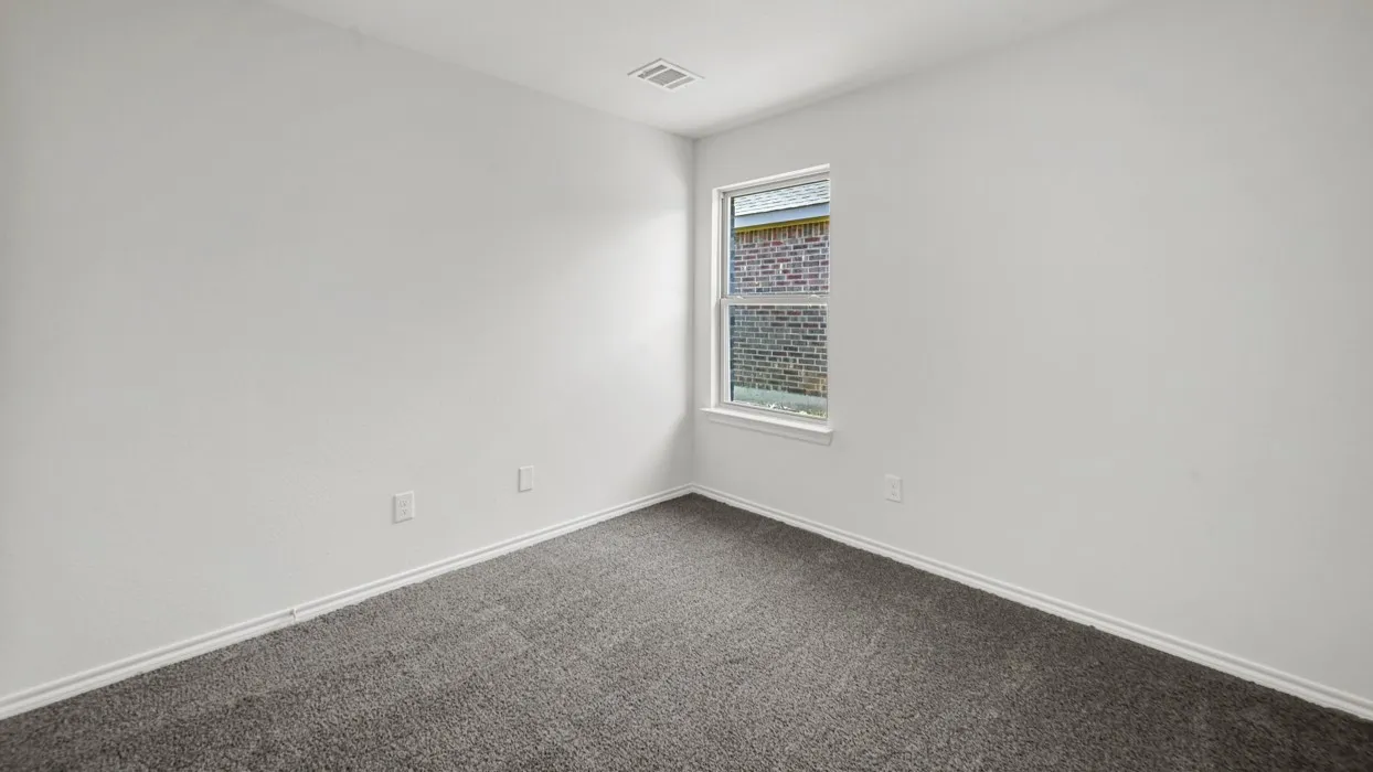 Bright room featuring a single window, white walls, dark gray carpeting, and white baseboards