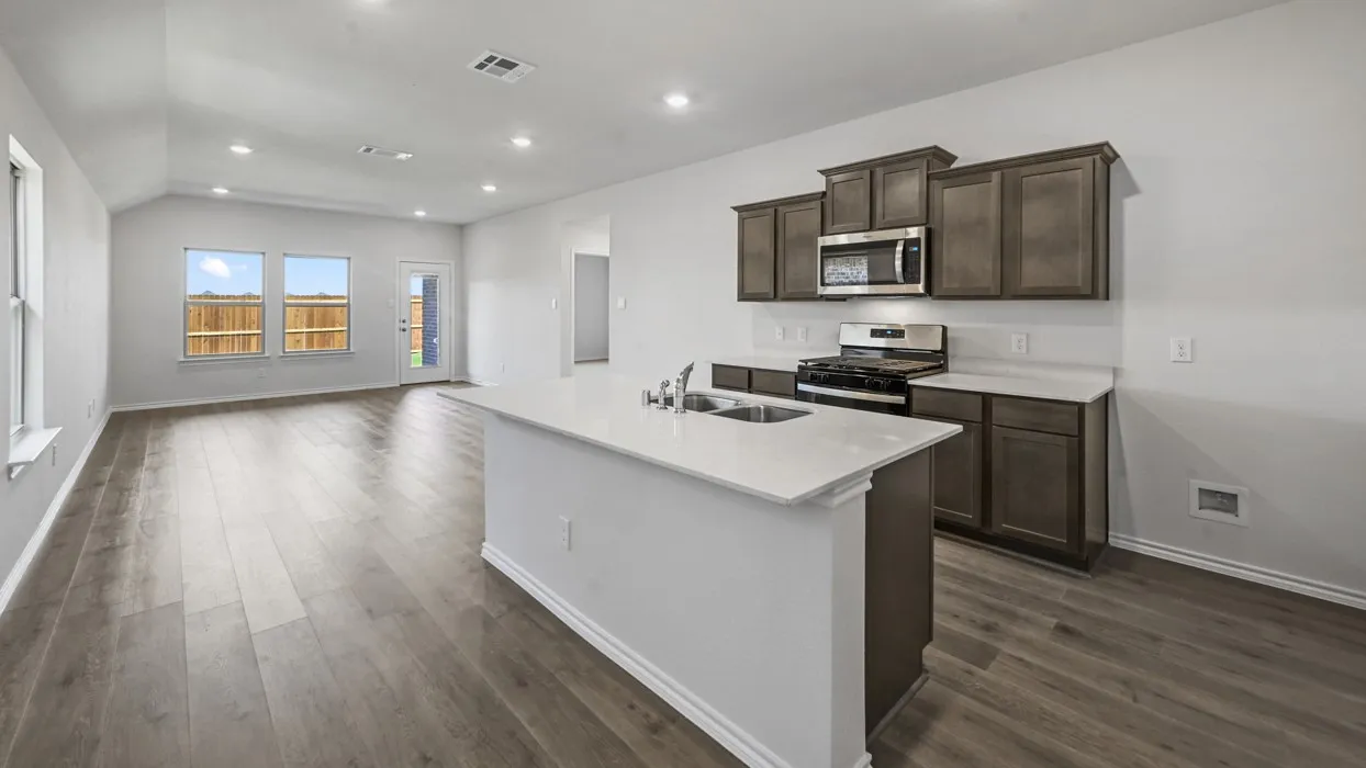 Open-concept kitchen and living area featuring wood-finish flooring, recessed lighting, and a kitchen island with an undermount sink